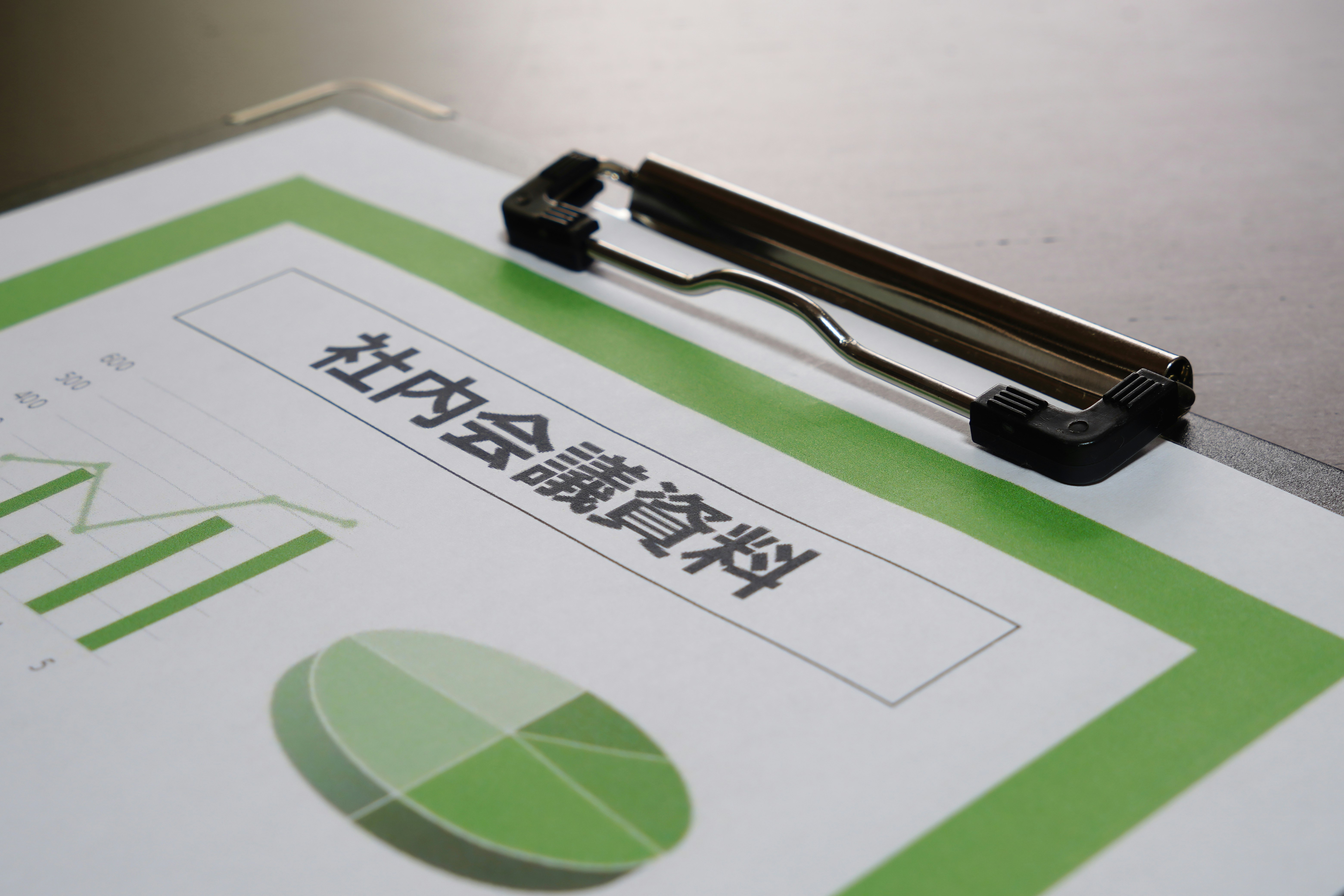 印有绿色图表的商务文件与带笔夹的夹板