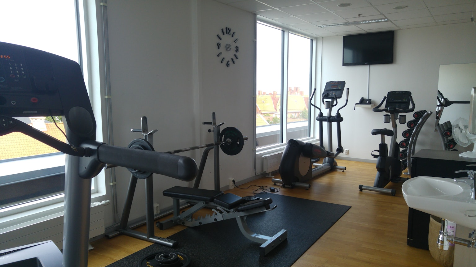 Sala de fitness luminosa con una caminadora y bicicletas de ejercicio