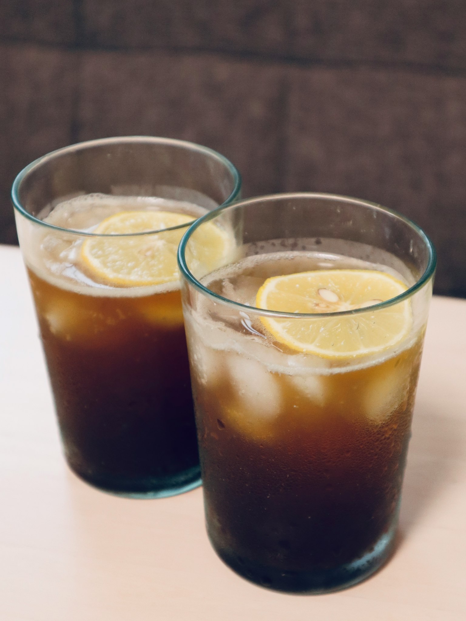 Two glasses of cold beverage with ice and lemon slices