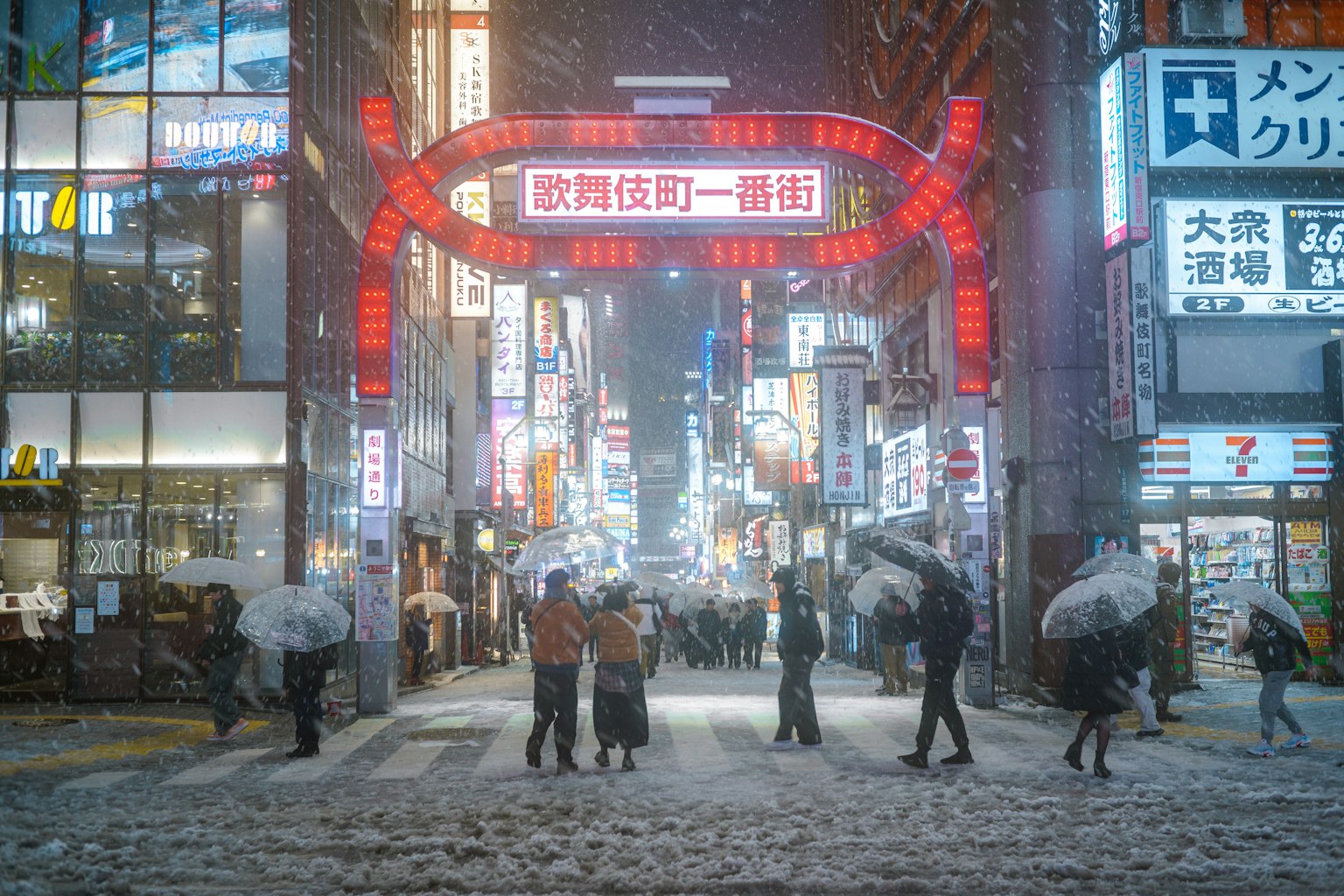 Scena di strada notturna innevata con insegne al neon e pedoni con ombrelli