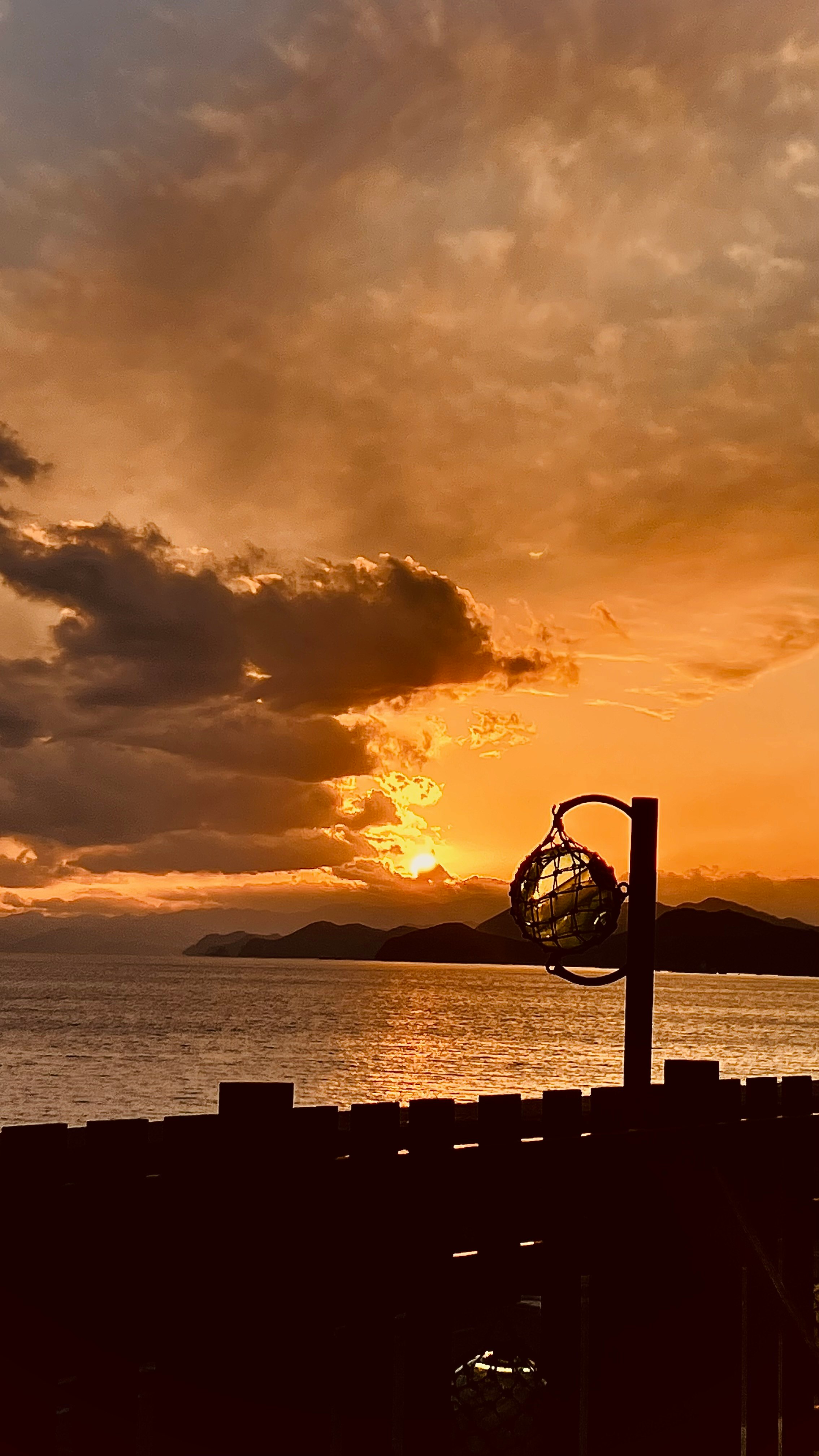 夕暮れの海辺に浮かぶ夕日と波止場の灯り