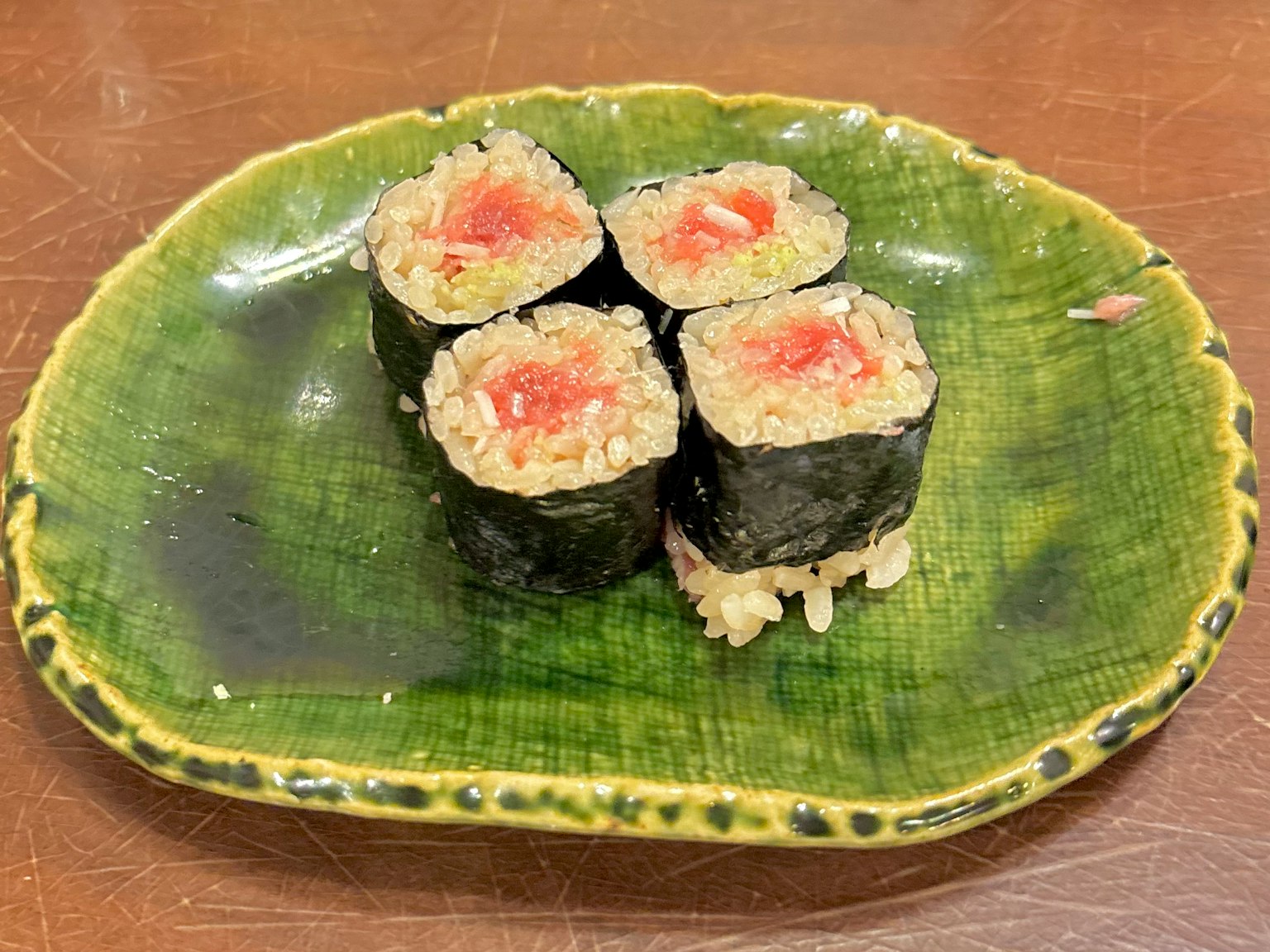 綠色盤子上的壽司卷，明顯的紅色魚餡