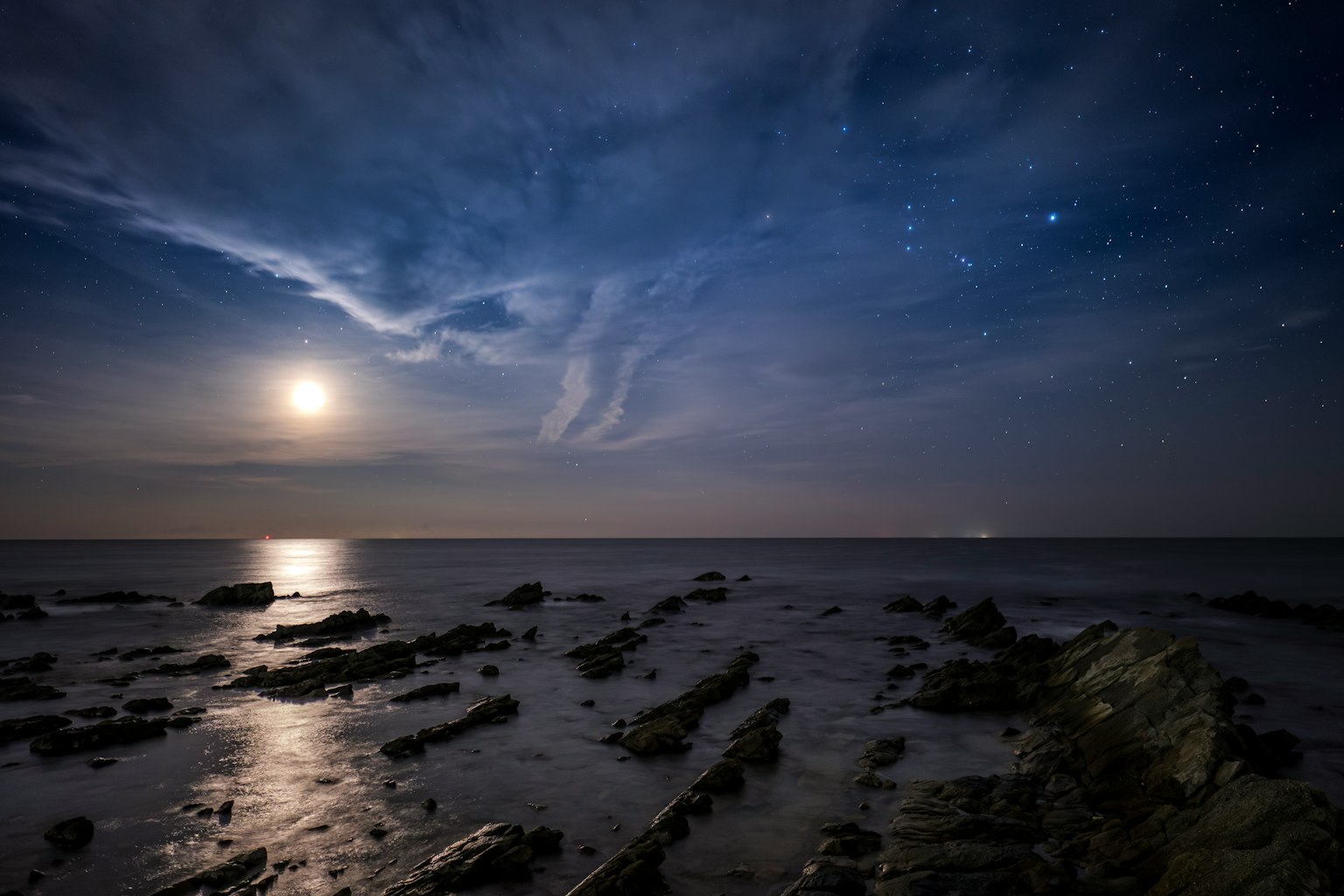 Paesaggio costiero sotto un cielo stellato con luce lunare