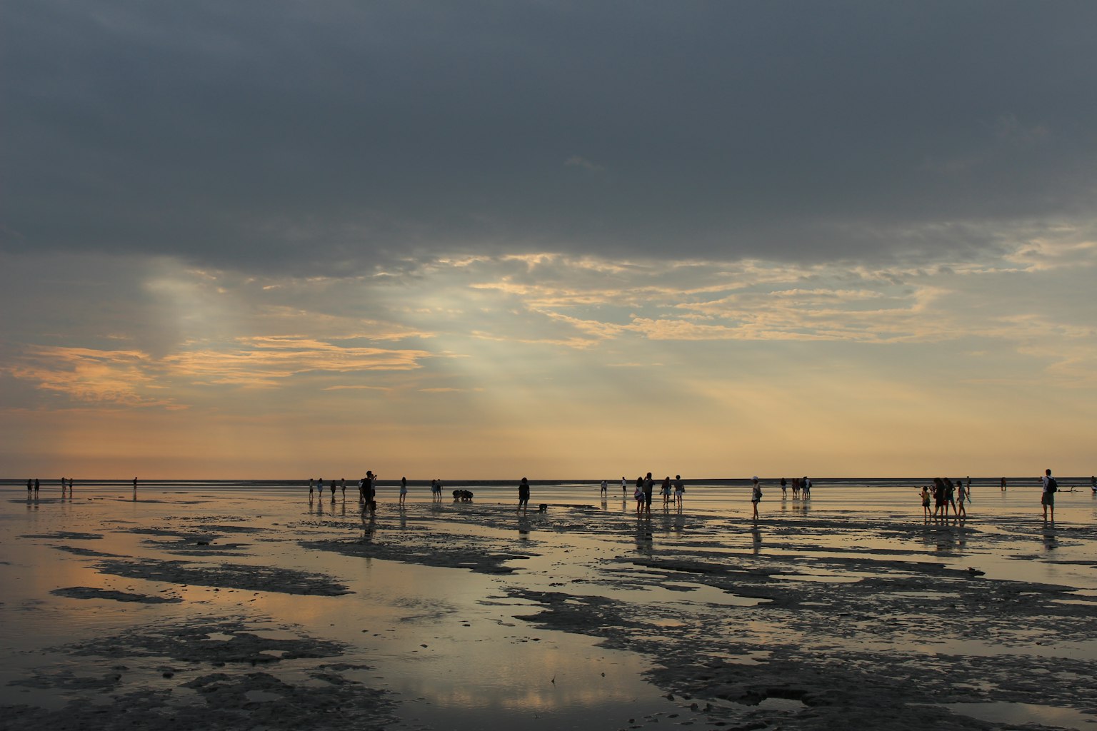 夕陽下在反射海岸上行走的人影