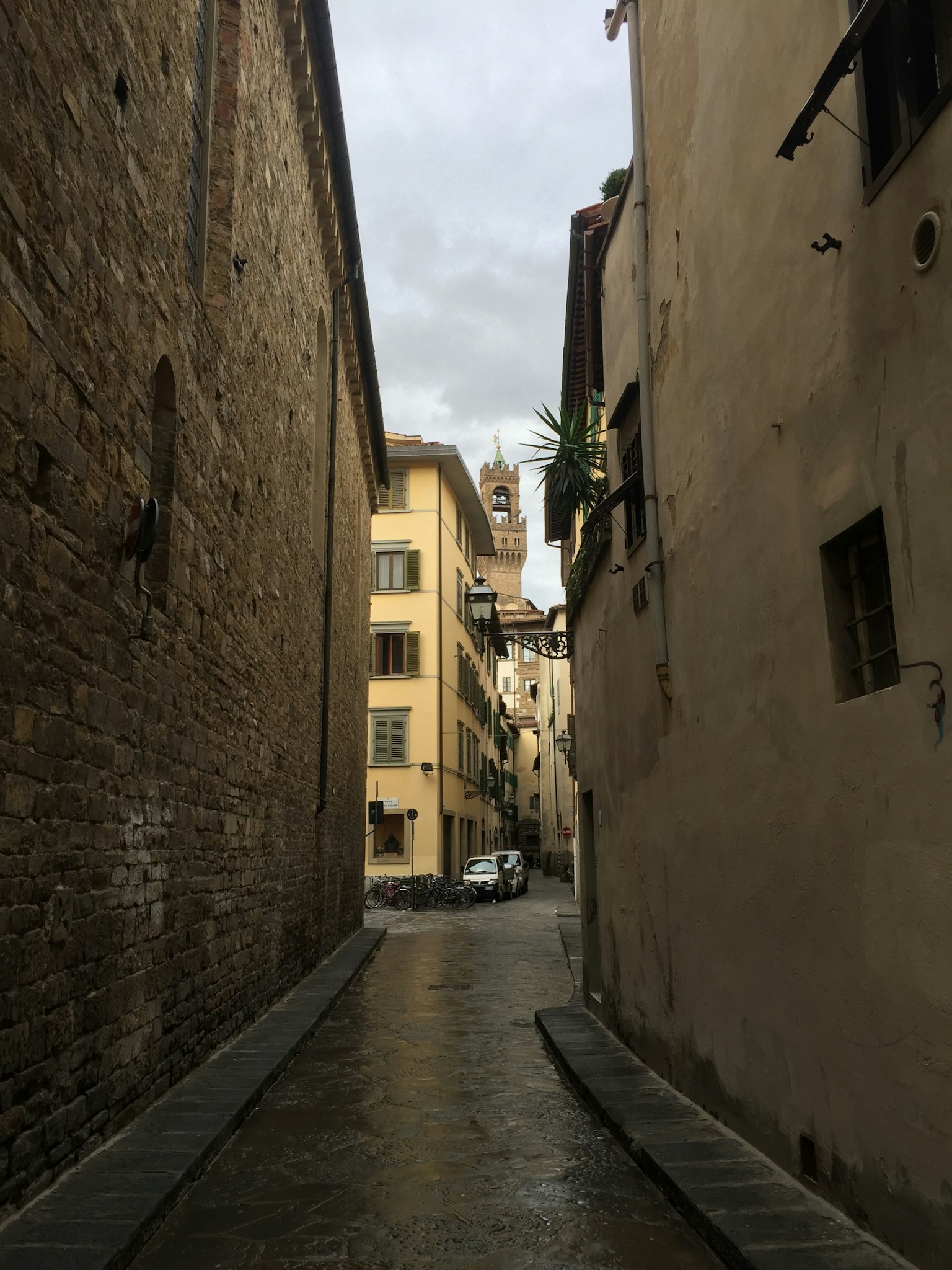 Narrow street in Florence with wet cobblestones and historic buildings