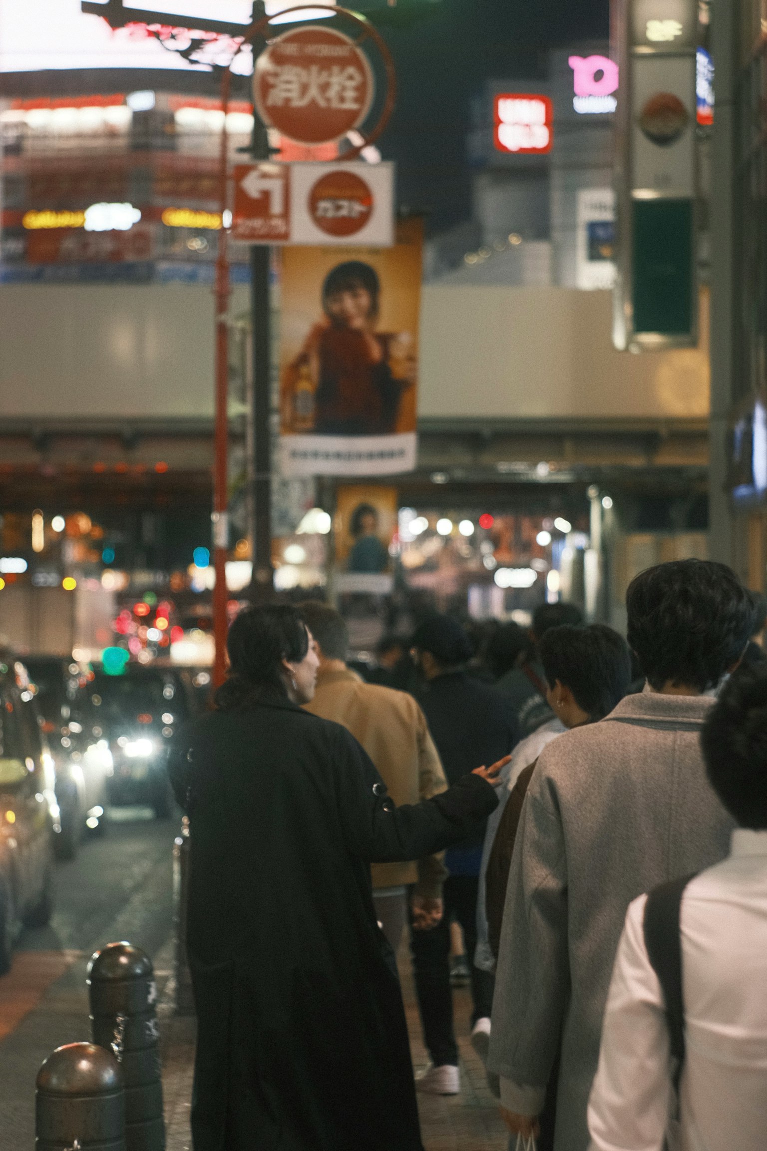 People walking on a city street at night with bright billboards