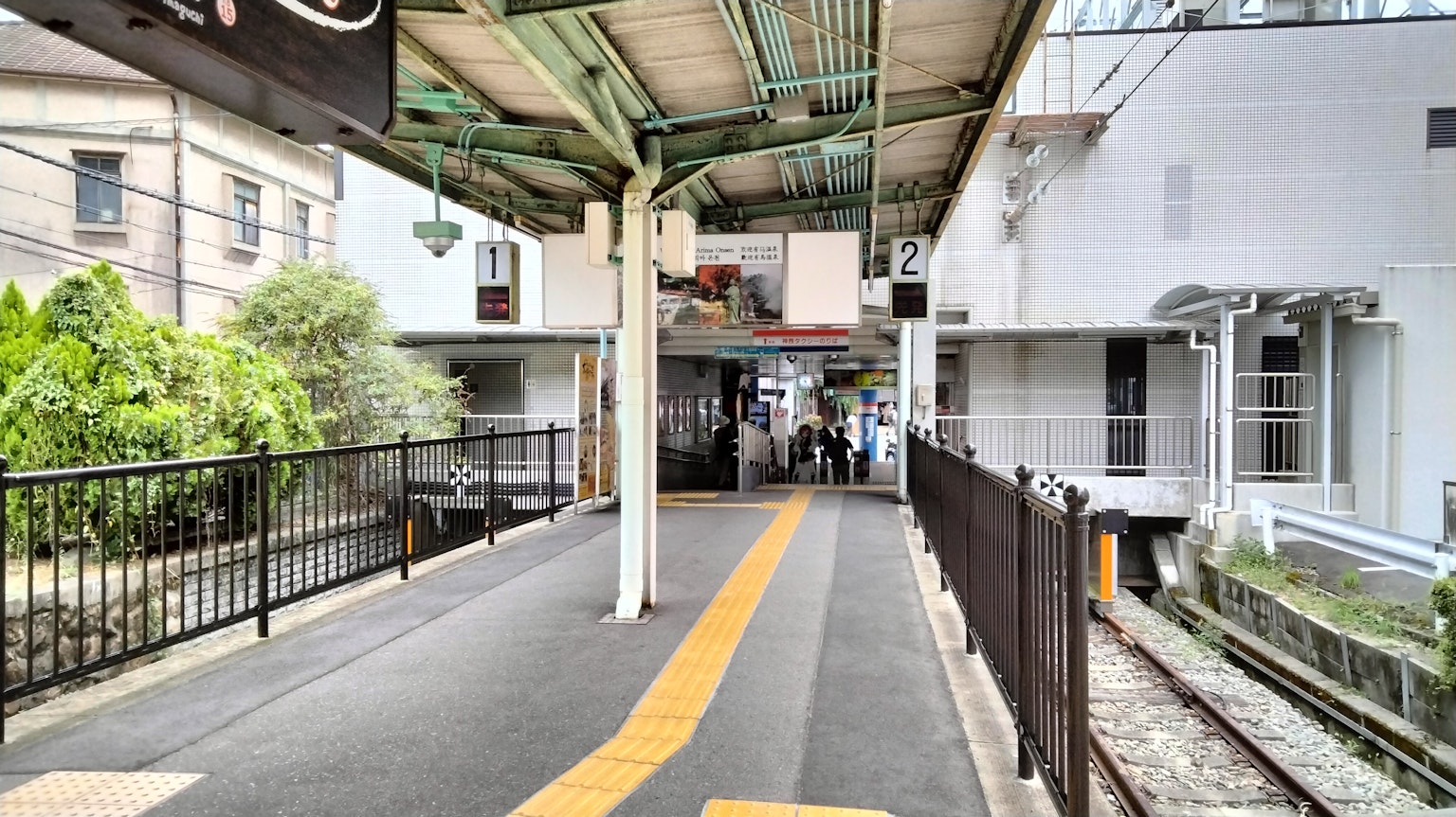ทัศนียภาพของplatformสถานีรถไฟที่มีพืชสีเขียวและอาคารสีขาว