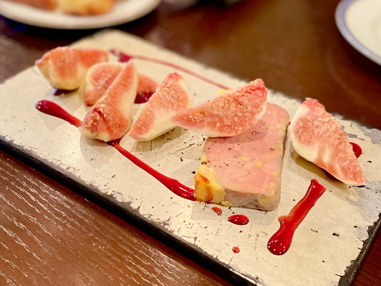 Un piatto con pâté cremoso guarnito con fichi freschi e glassato con salsa di bacche
