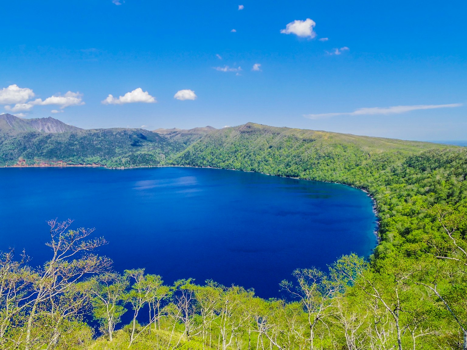 Vue panoramique d'un lac bleu entouré de montagnes verdoyantes