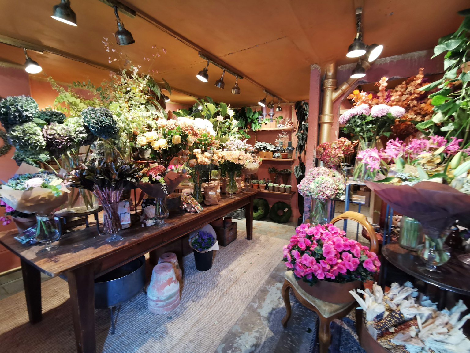 Interno di un negozio di fiori con fiori colorati e piante esposte su tavoli illuminazione calda e atmosfera accogliente