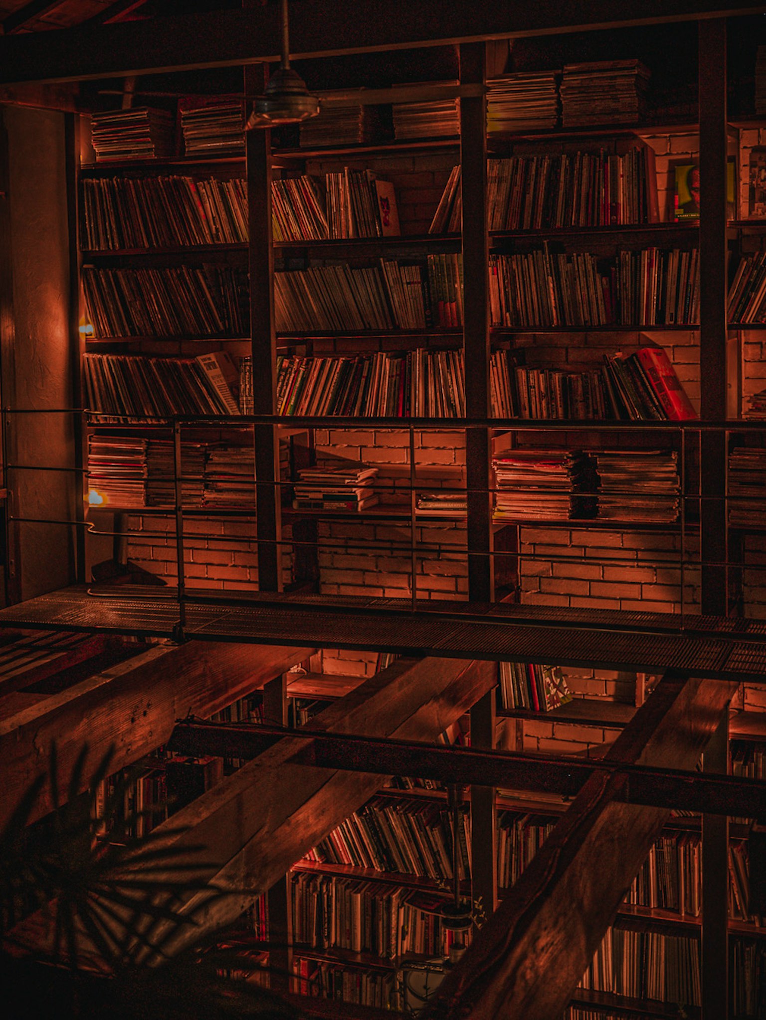 Dimly lit library with wooden bookshelves filled with books and a reflecting table