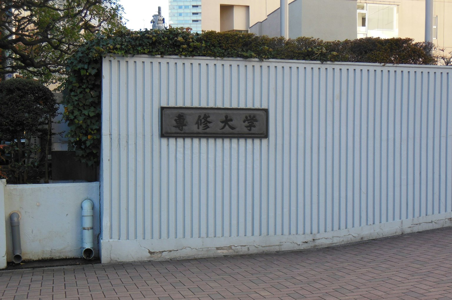 Vue extérieure d'un mur blanc avec un panneau universitaire