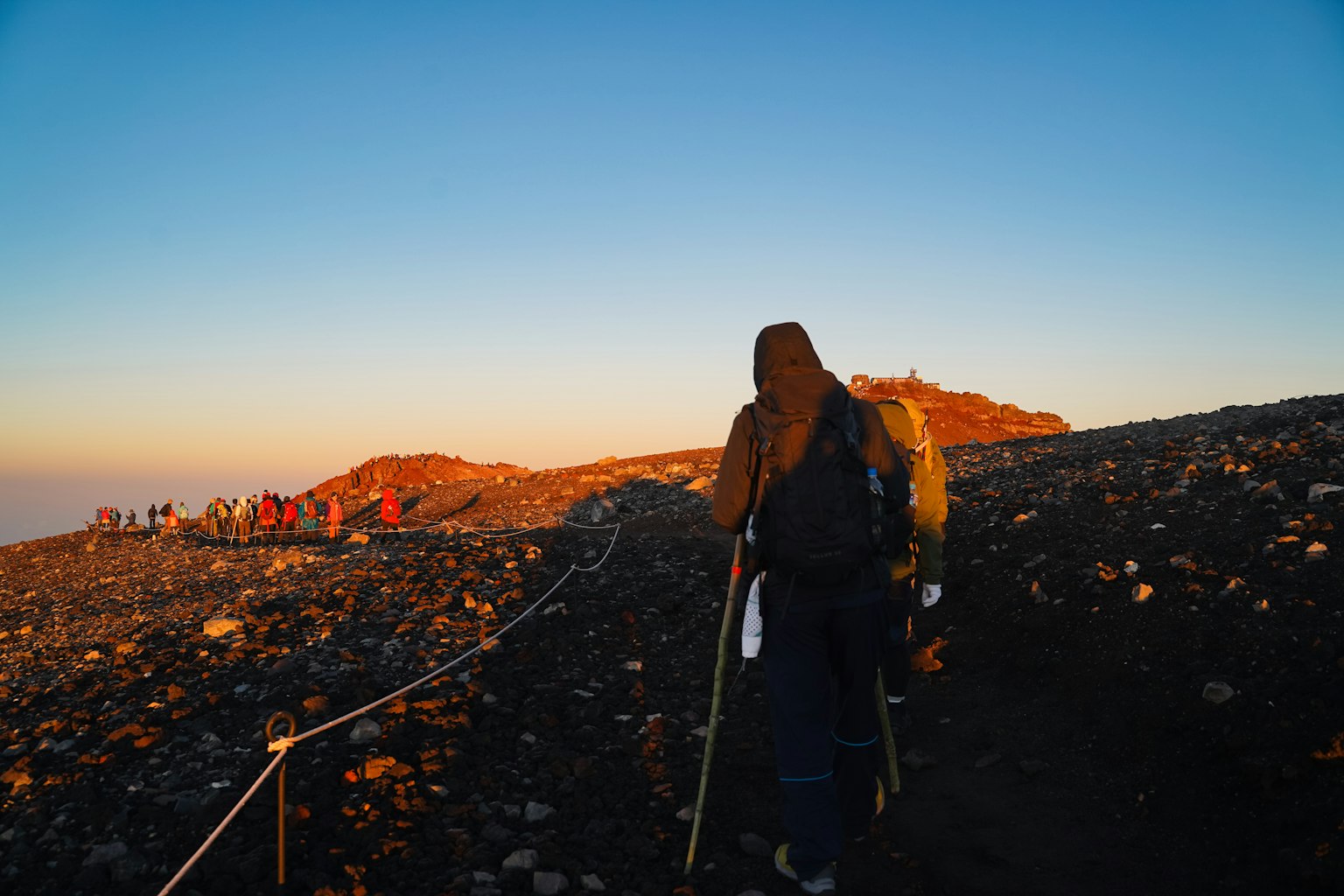 Randonneurs sur un sentier avec un ciel au coucher de soleil