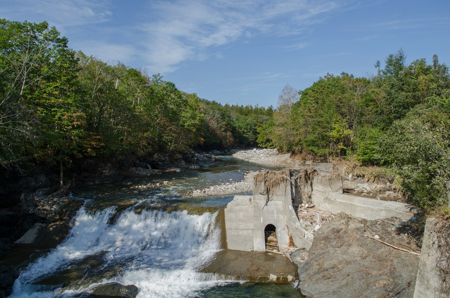 Vue panoramique d'une rivière avec une cascade entourée d'arbres verts et d'un environnement serein