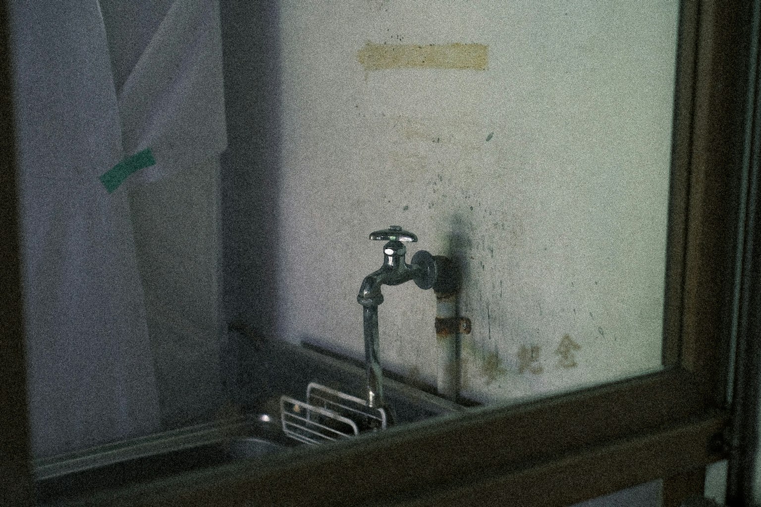 Imagen de un fregadero y grifo antiguos vistos a través de una ventana