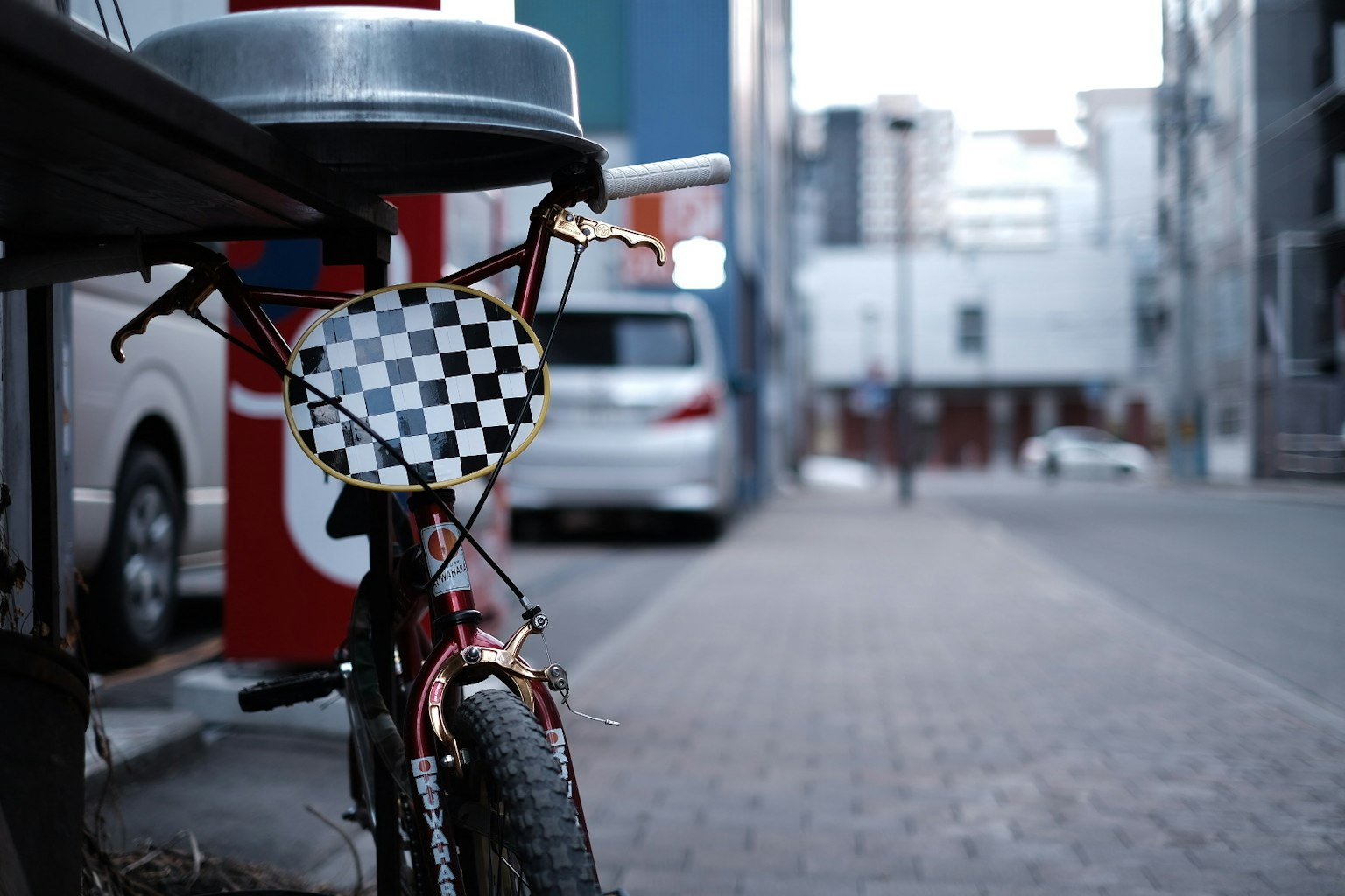 Ein Fahrrad, das auf der Straße geparkt ist, mit einem Korb im Schachbrettmuster