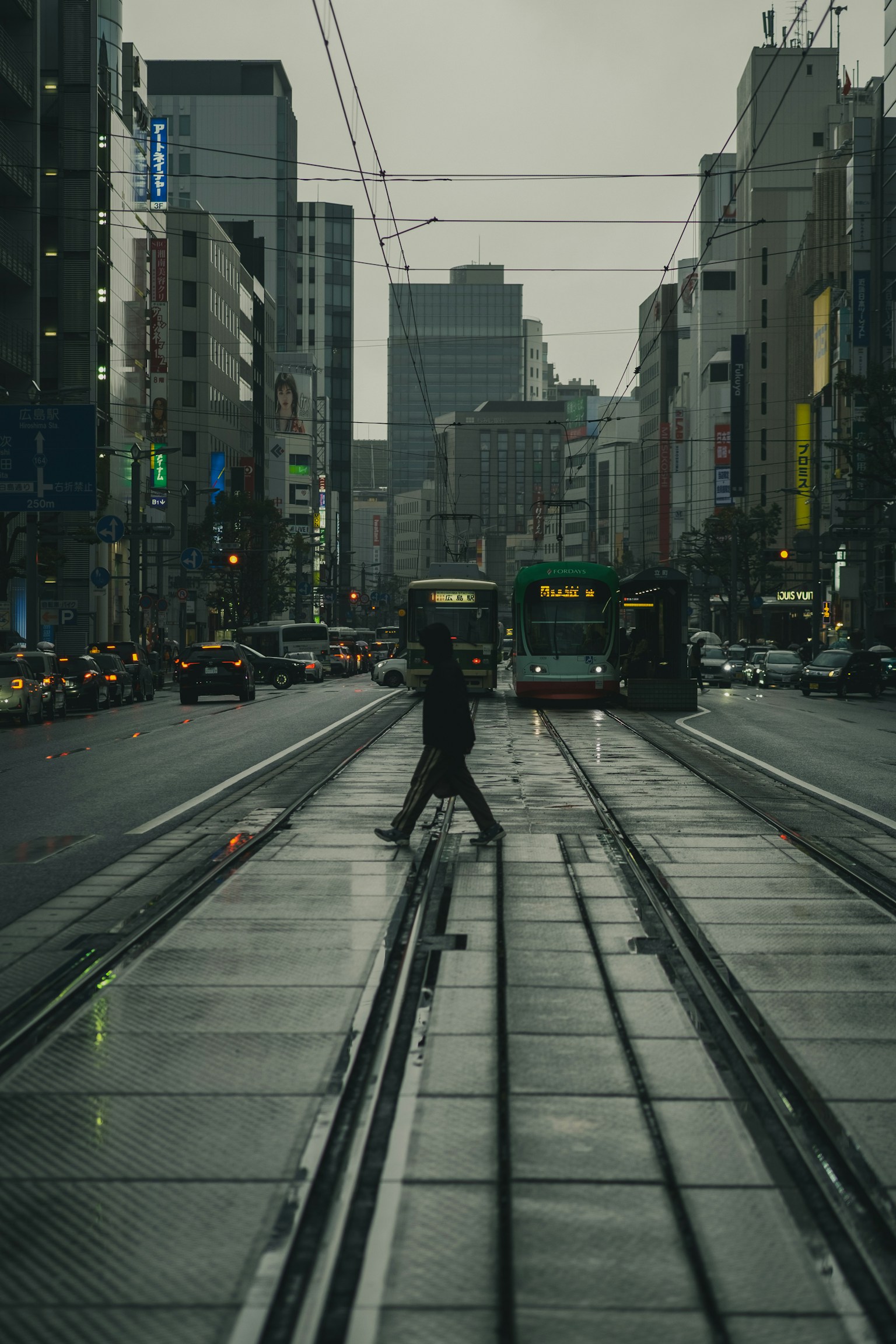 Une silhouette d'une personne traversant des rails de tramway avec un décor urbain