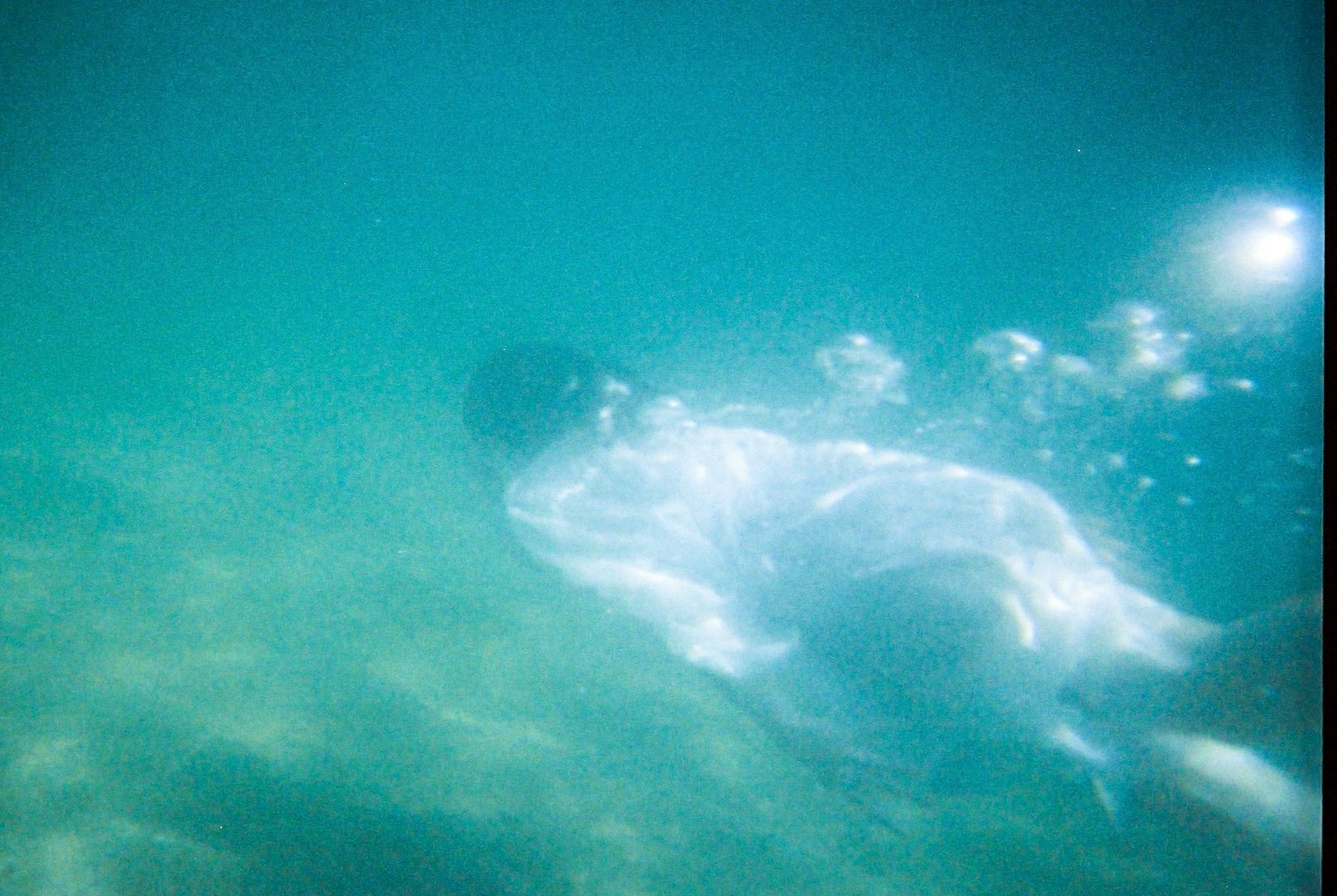 Silhouette di una persona che nuota sott'acqua con bolle