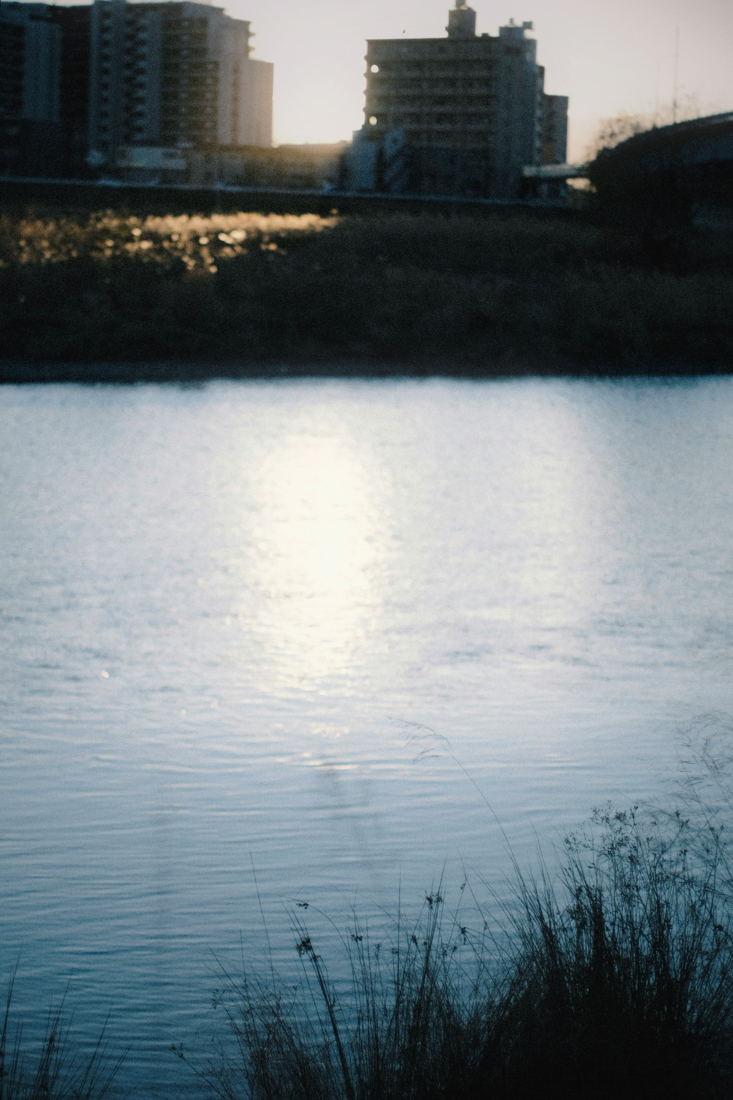 Kanal bei Dämmerung mit ruhigem Wasser und fernen Wohnhochhäusern