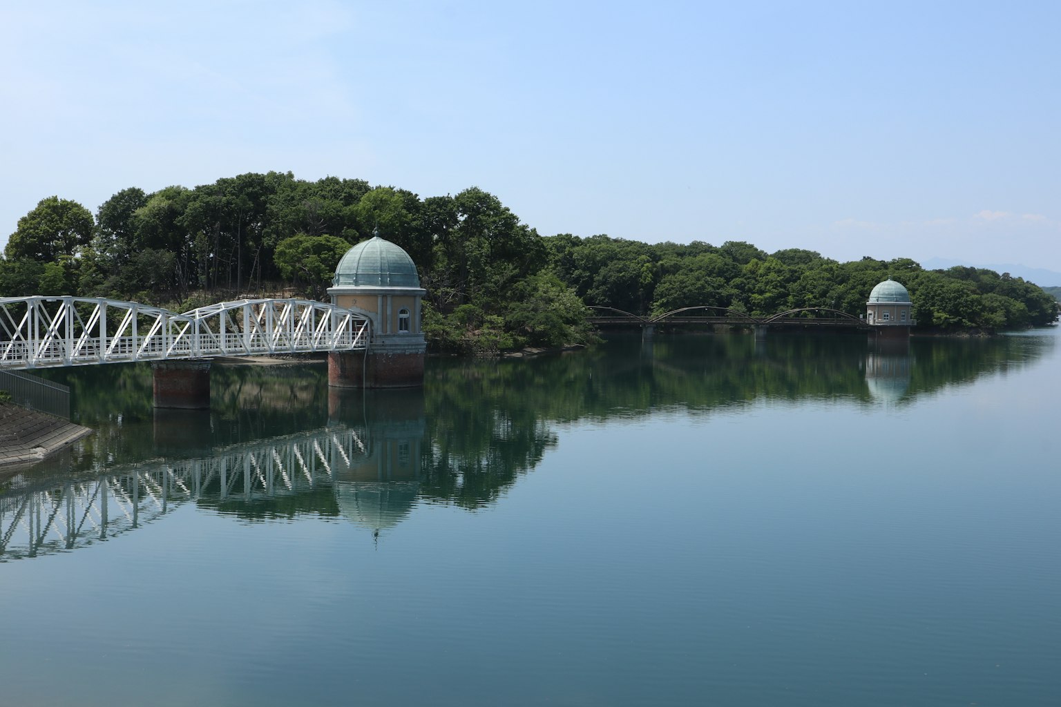 ทิวทัศน์ที่สวยงามของทะเลสาบที่เงียบสงบพร้อมสะพานและโครงสร้างรูปโดม