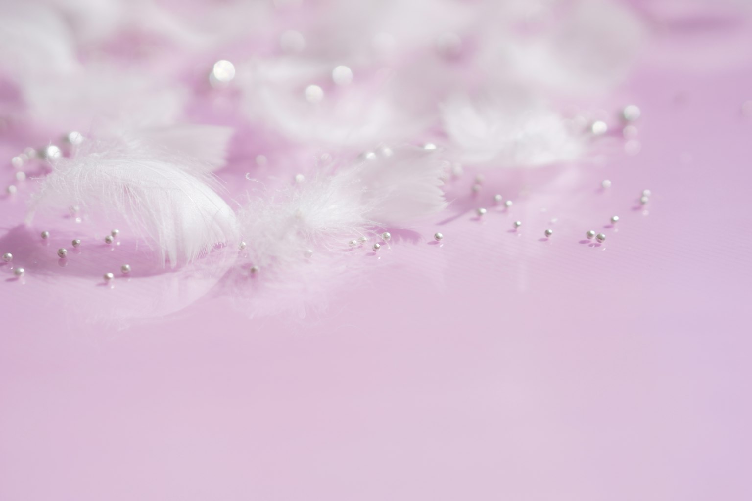 Petali bianchi delicati che galleggiano su uno sfondo rosa chiaro con gocce d'acqua