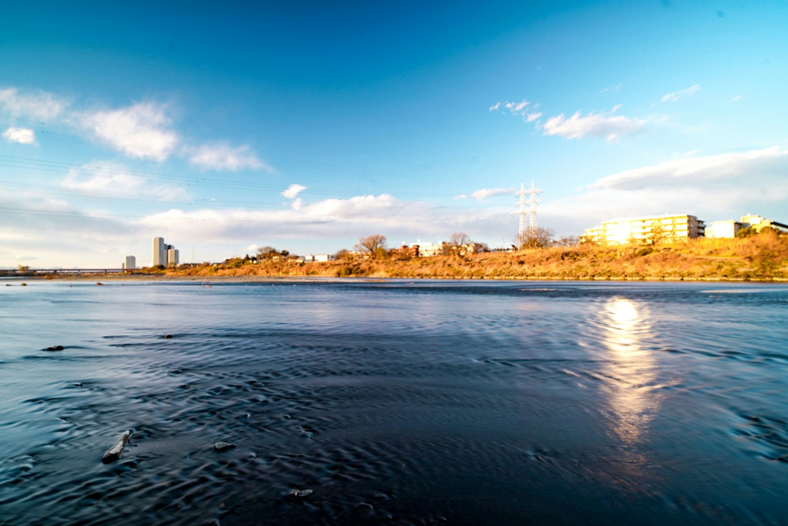 Calm river landscape under blue sky with reflective light