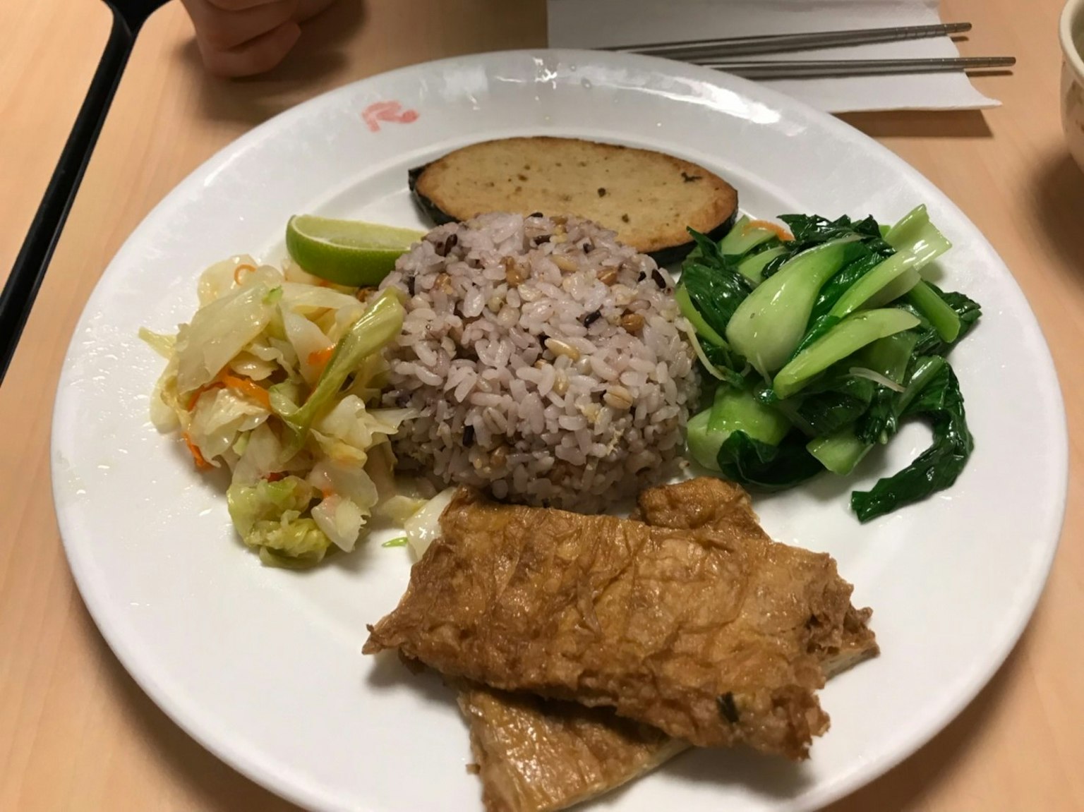 盘子上有紫米、炒蔬菜、炸鱼、青菜、青柠片和烤香蕉
