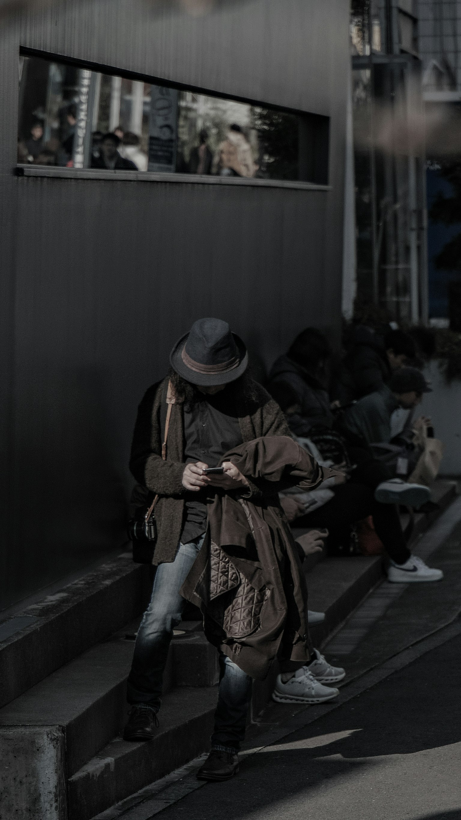 Person, die ein Smartphone vor einem dunklen Hintergrund benutzt, mit anderen in der Nähe
