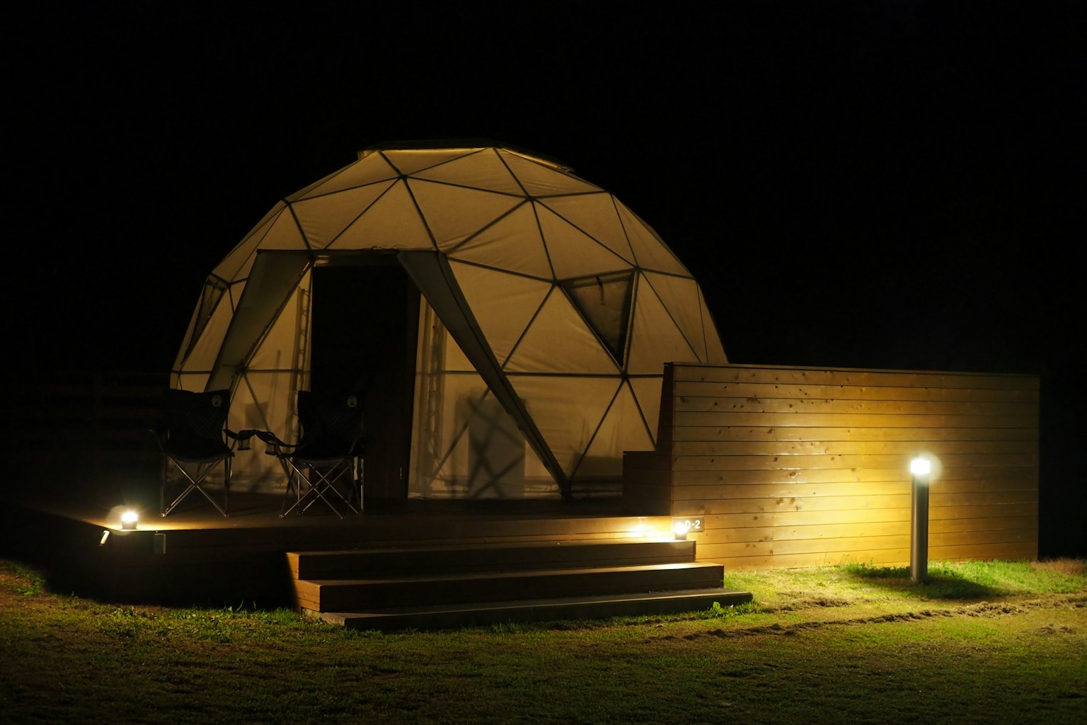 Night view of a geodesic dome tent with wooden deck