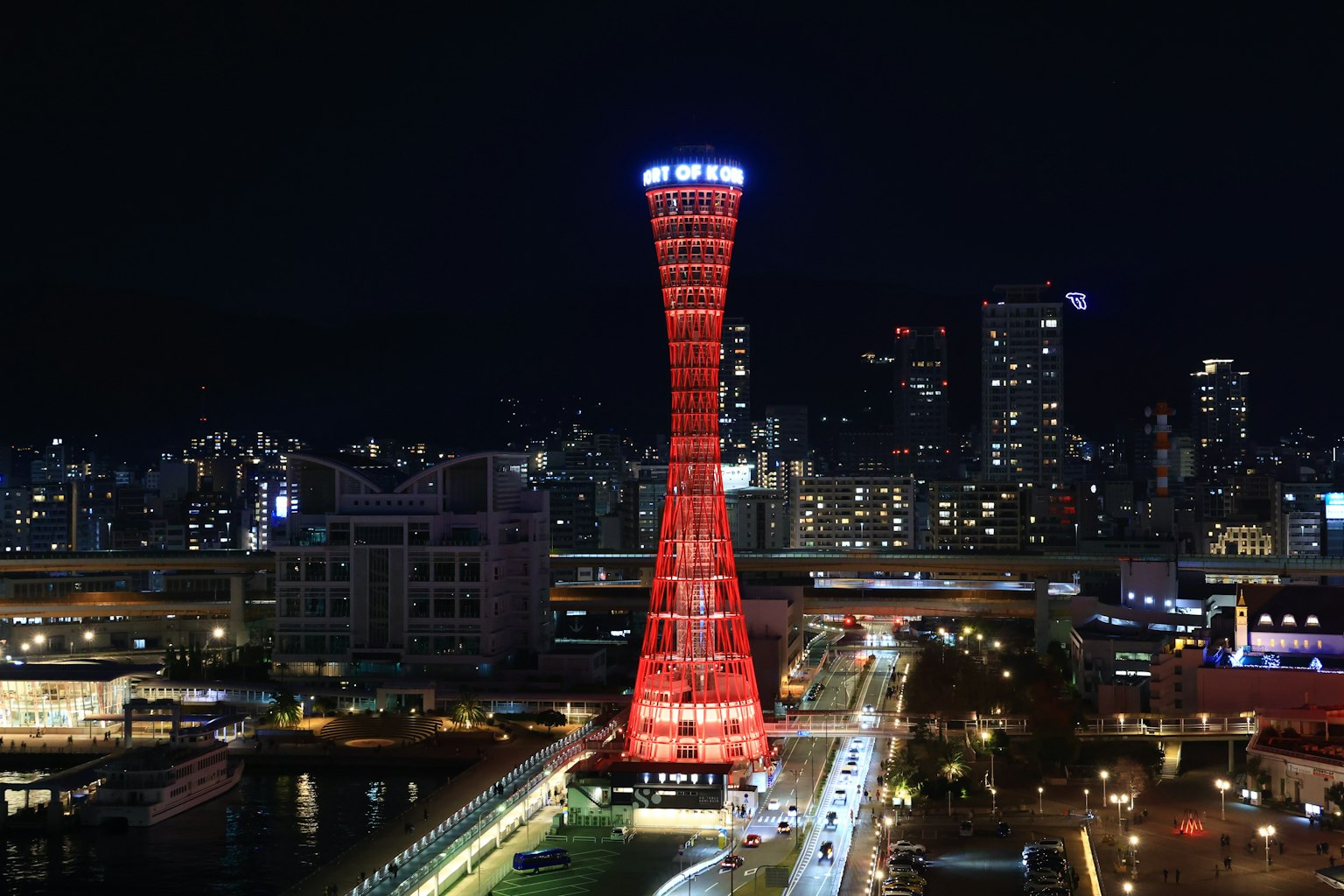 Tour du port de Kobe illuminée en rouge la nuit avec la ligne d'horizon de la ville