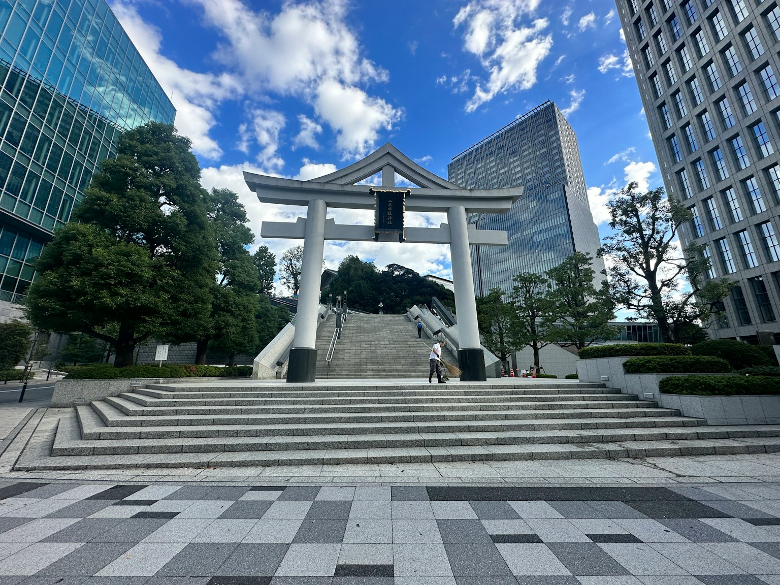 Puerta torii y escaleras bajo un cielo azul con edificios modernos