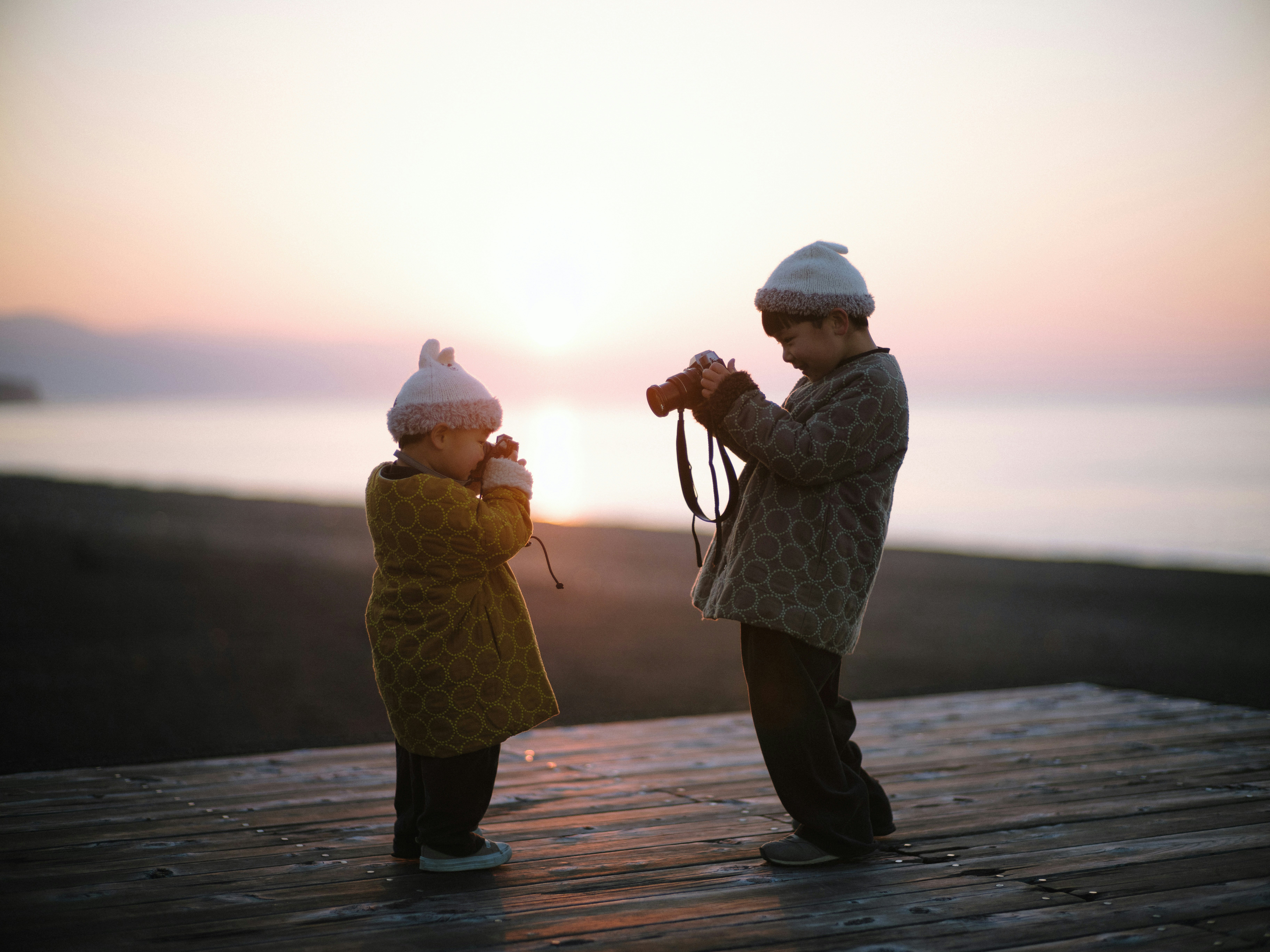 silhouette of a parent and child walking hand in hand on a seaside at sunset