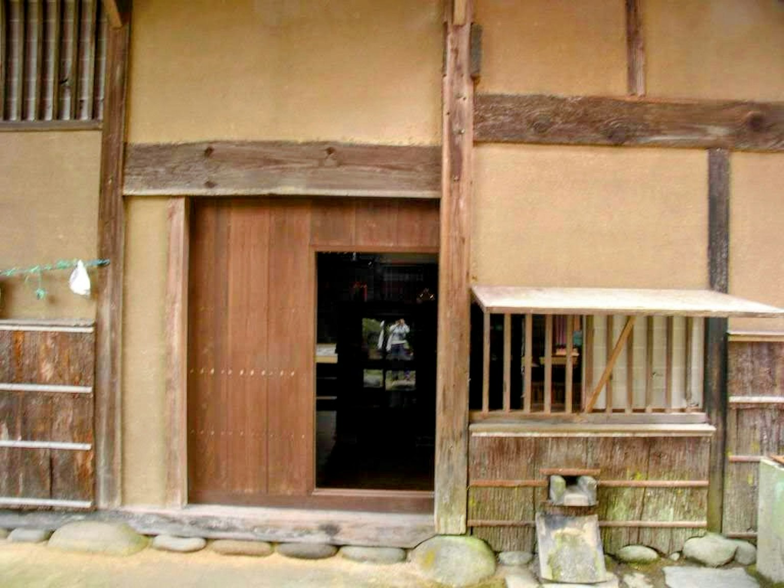 Pintu masuk rumah Jepang tradisional dengan pintu kayu dan dinding tanah