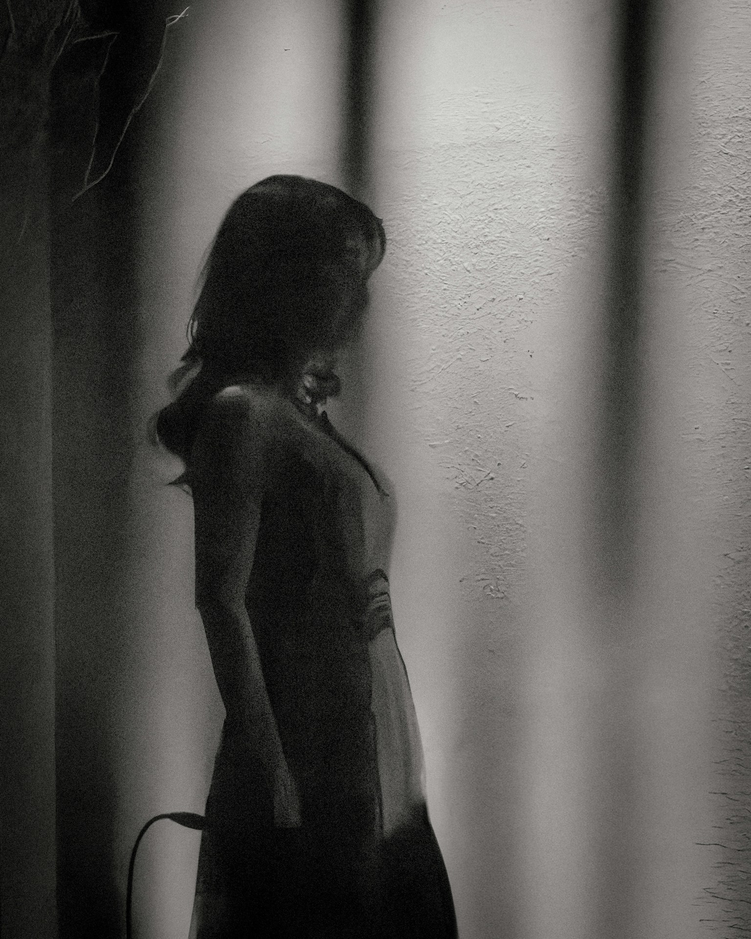 女性のシルエットが薄暗い背景に浮かび上がるモノクロ画像