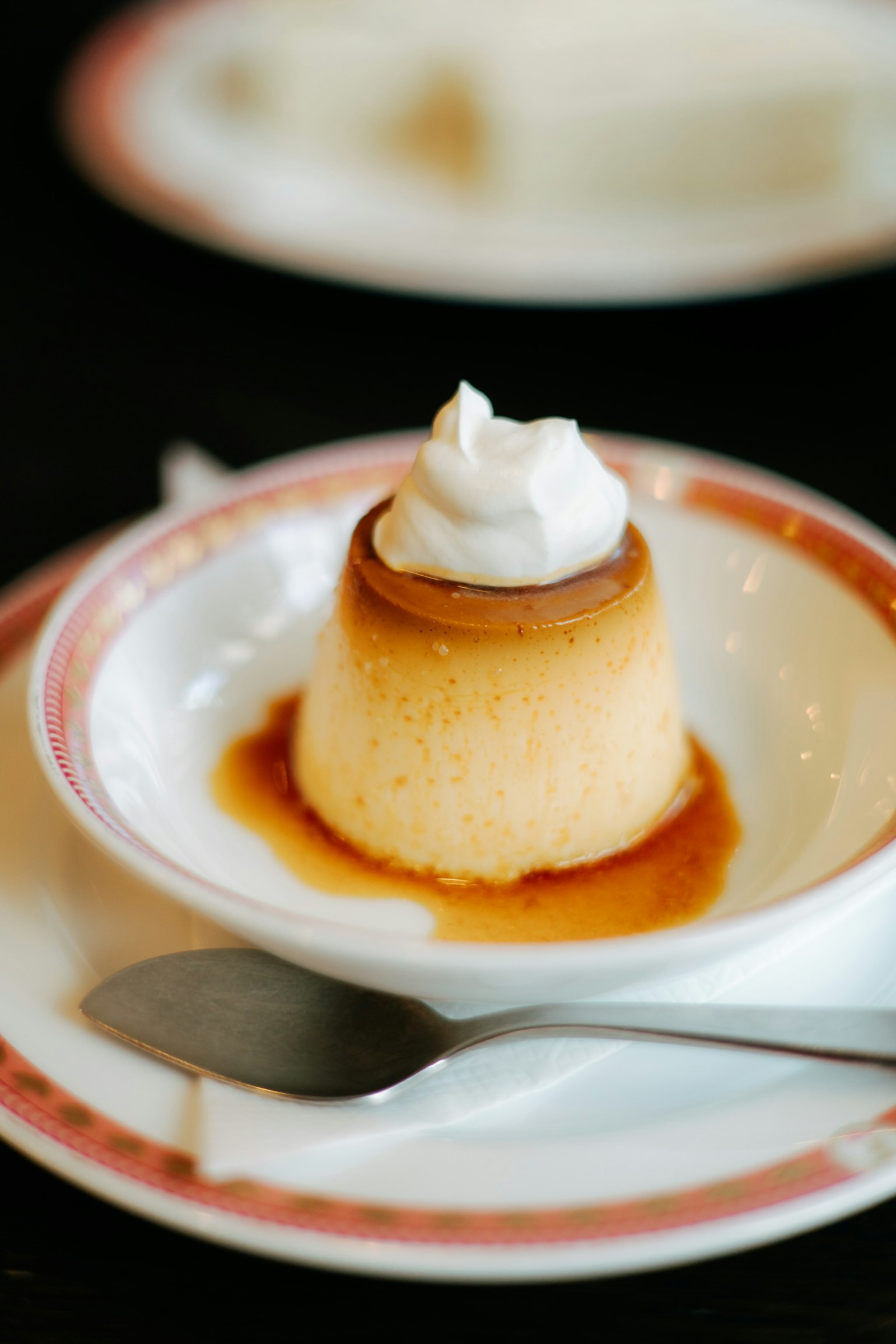 Flan krim dengan krim kocok di atas piring dekoratif dengan saus karamel