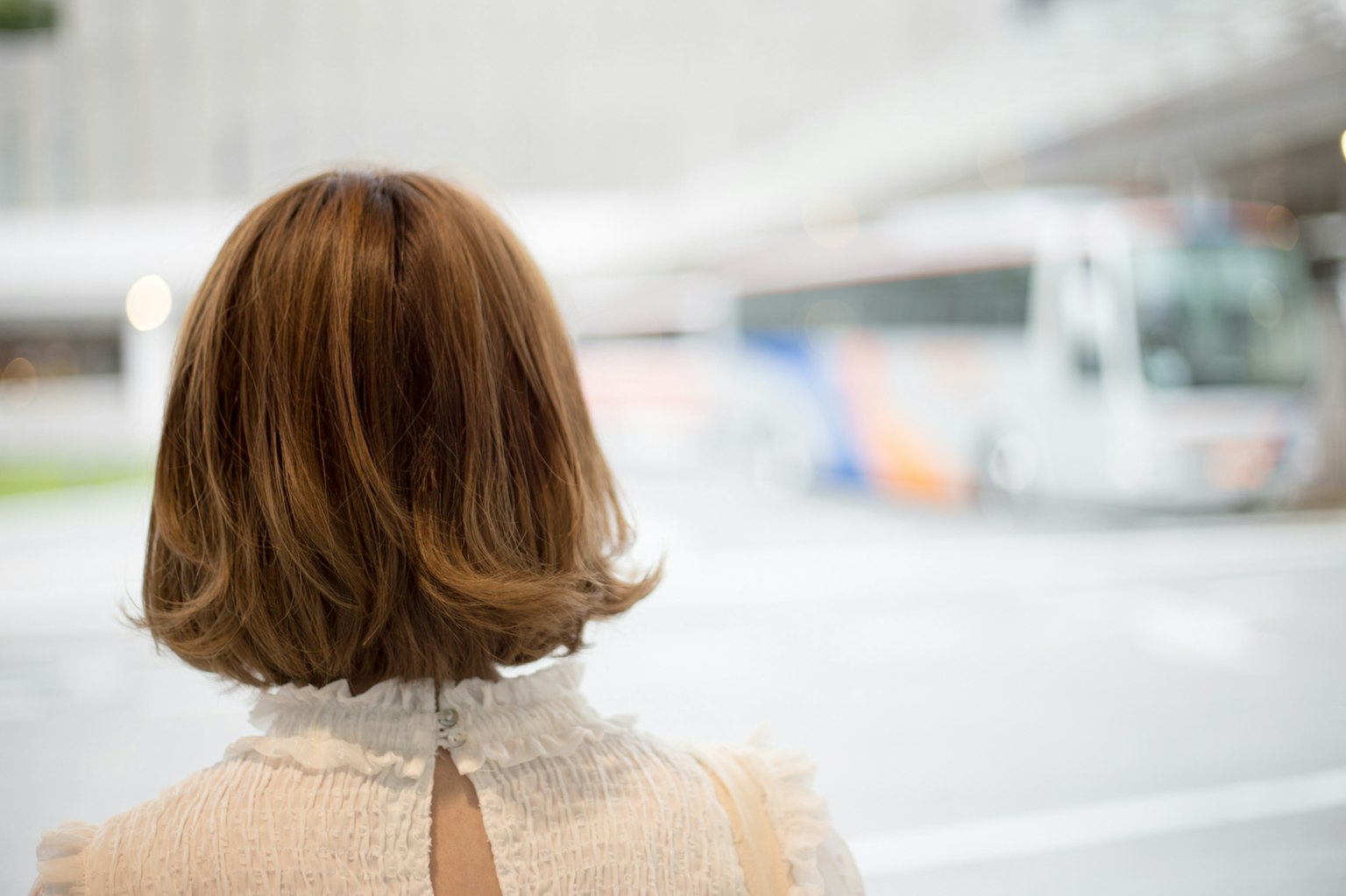 Una mujer esperando un autobús de espaldas