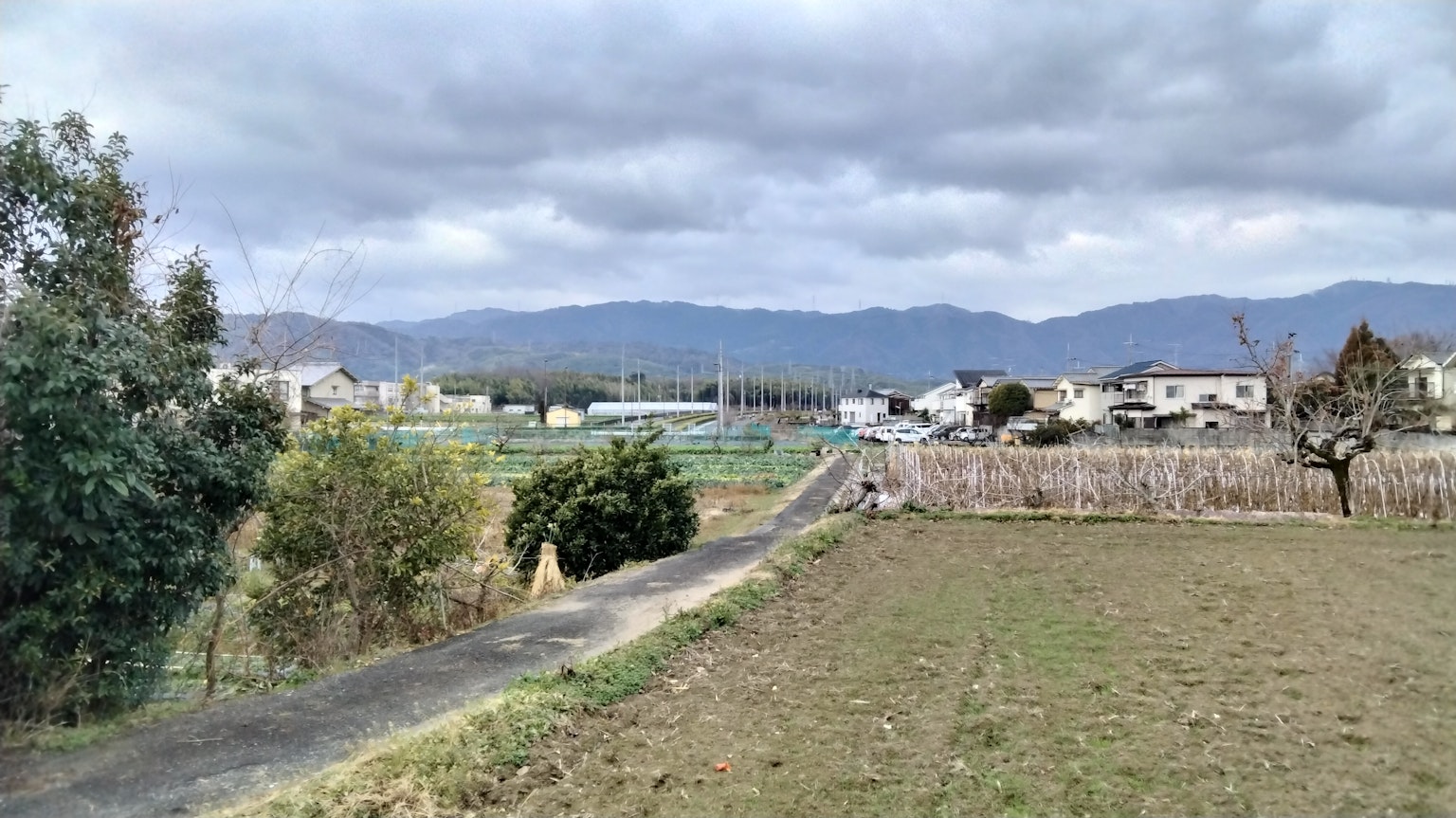 Rural landscape with mountains in the distance cloudy sky green fields and a pathway