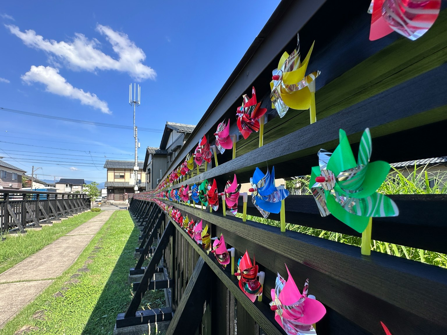 Colorful decorations along a black fence under a blue sky