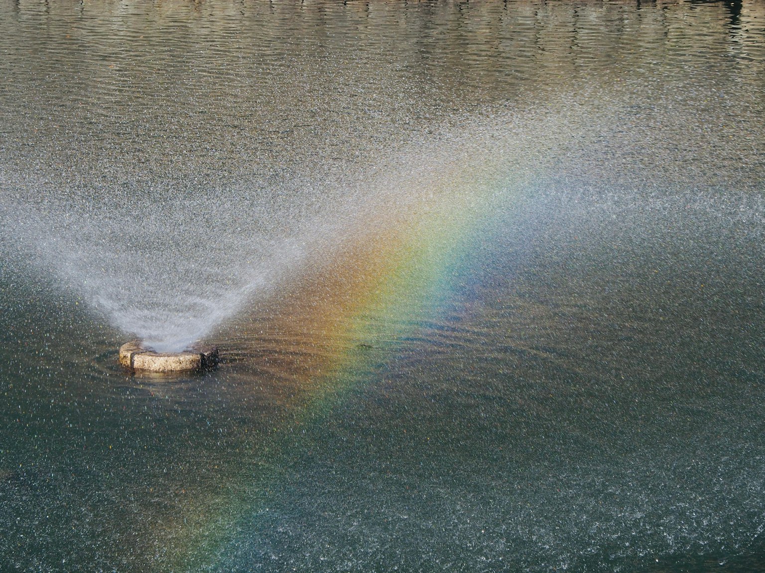 Schöne Szene mit einem Regenbogen und einem Brunnen auf der Wasseroberfläche