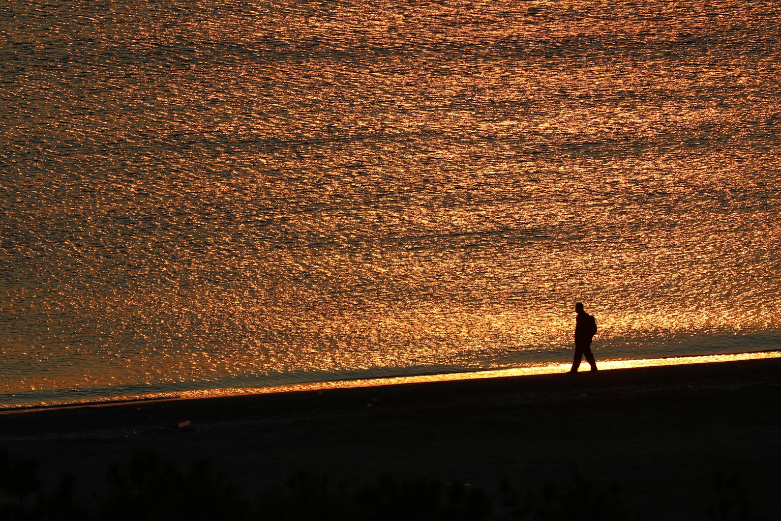 夕阳下在海滩上散步的人影