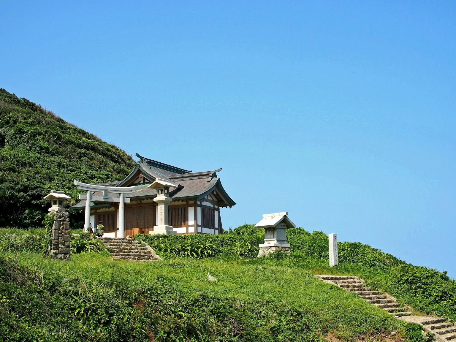 Traditioneller japanischer Tempel in üppigem Grün auf einem Hügel