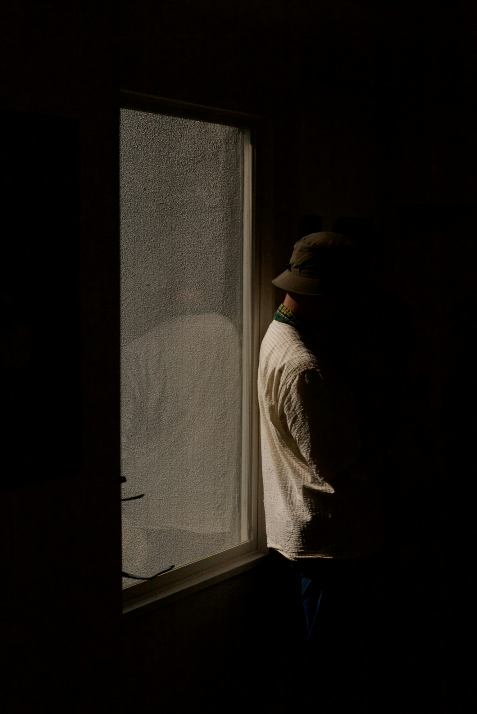 Silhouette of a person standing by a window in a dark room