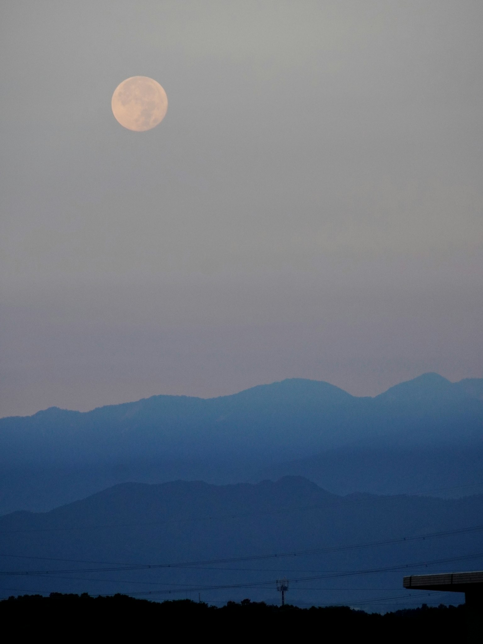 Luna piena sopra montagne blu al crepuscolo