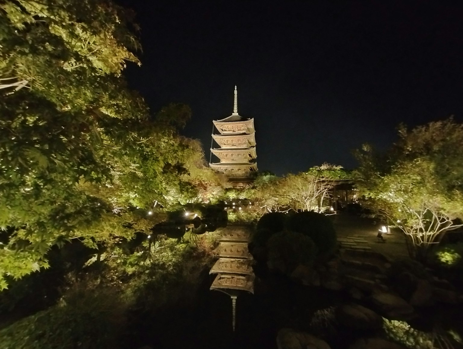 Pagoda illuminata che si riflette in un sereno giardino giapponese di notte