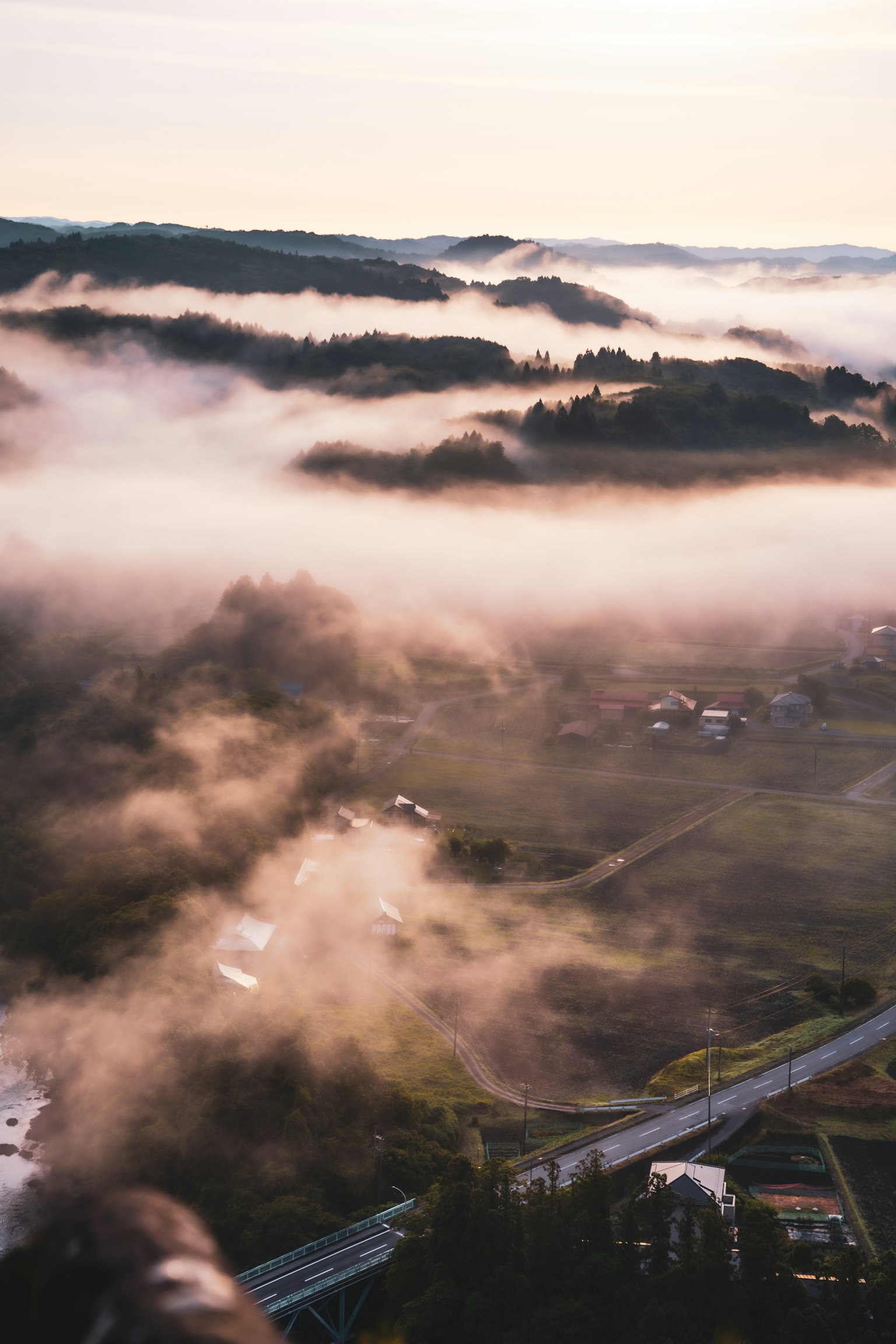 Una vista panoramica di colline e valli coperte di nebbia con case e strade in lontananza