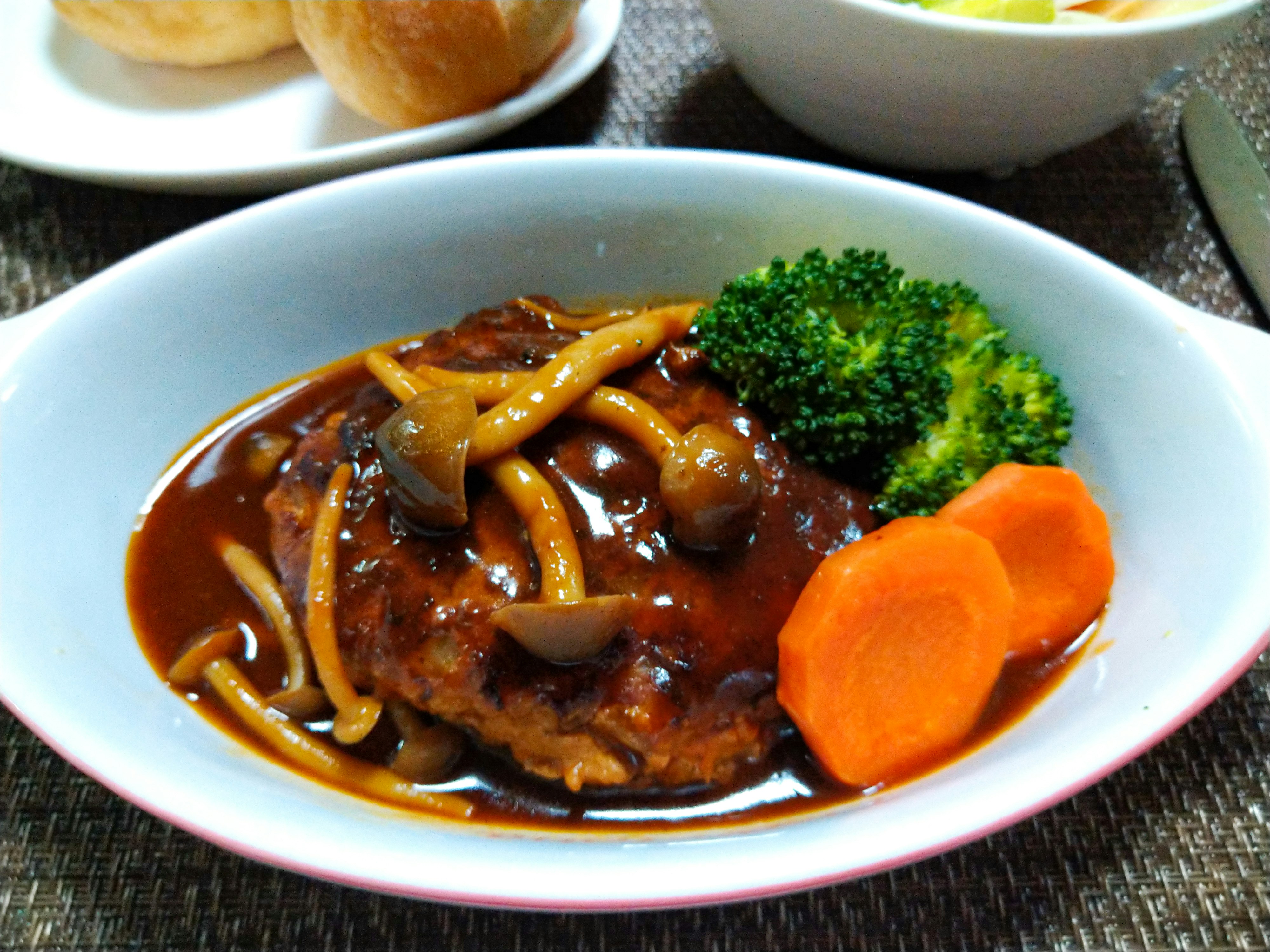 Hamburger steak with sauce, carrot and broccoli on a plate