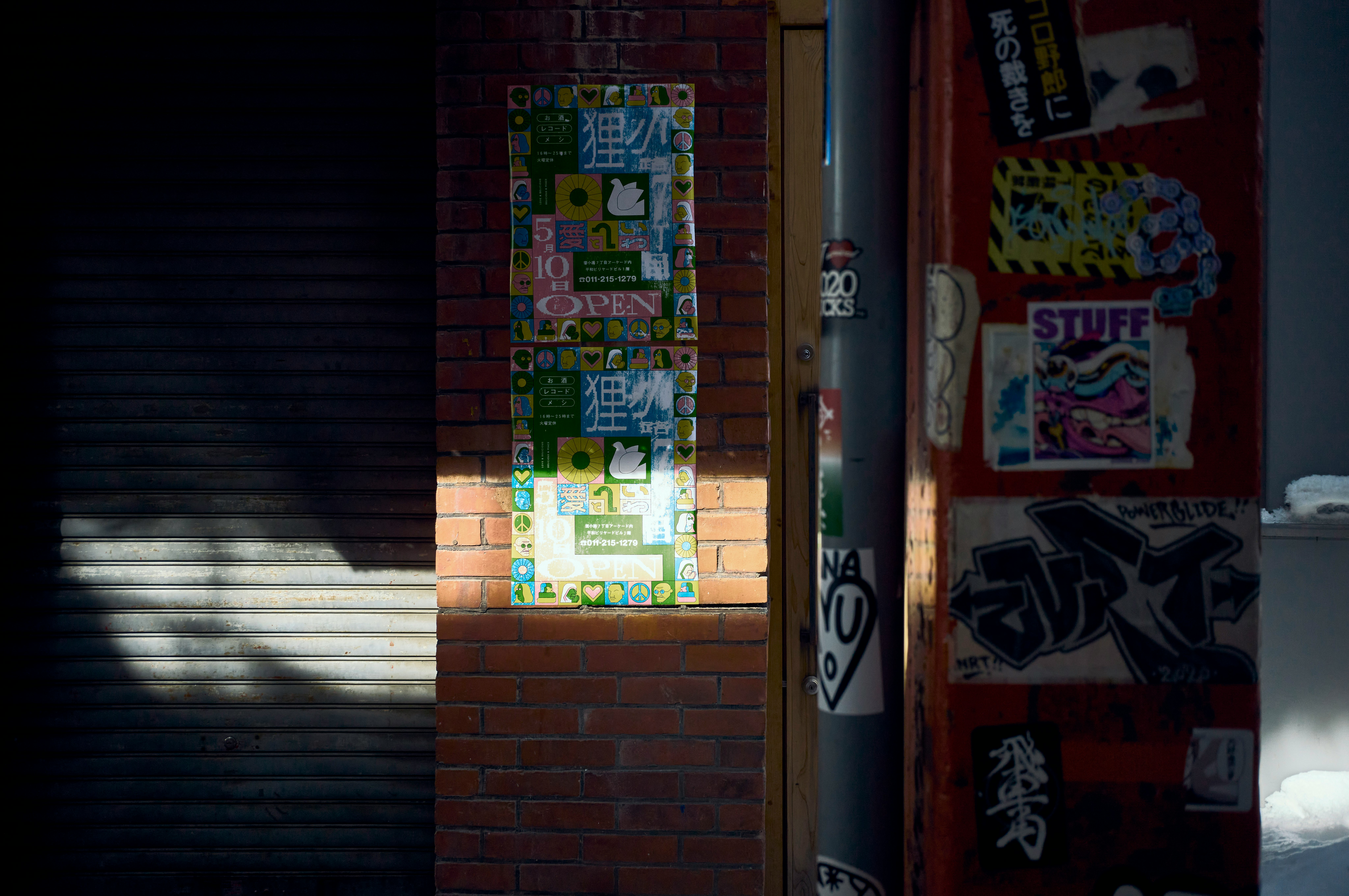 entrada de un callejón con carteles coloridos y graffiti en un muro de ladrillo