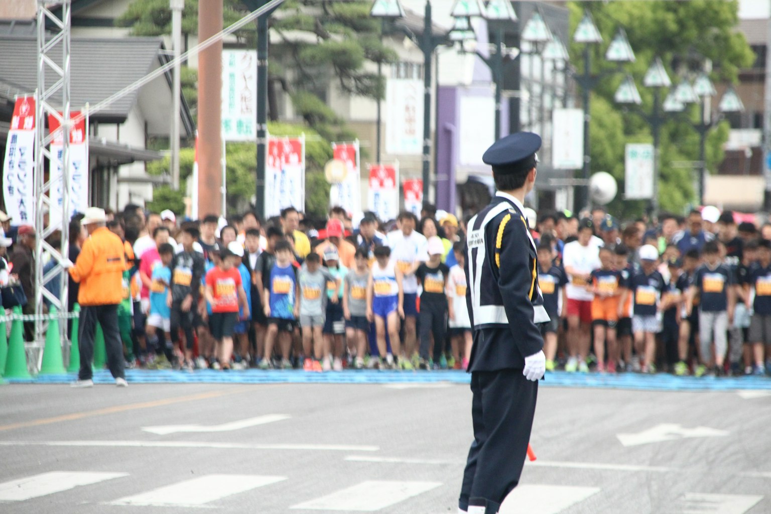 A police officer directing traffic at a marathon event with many runners present