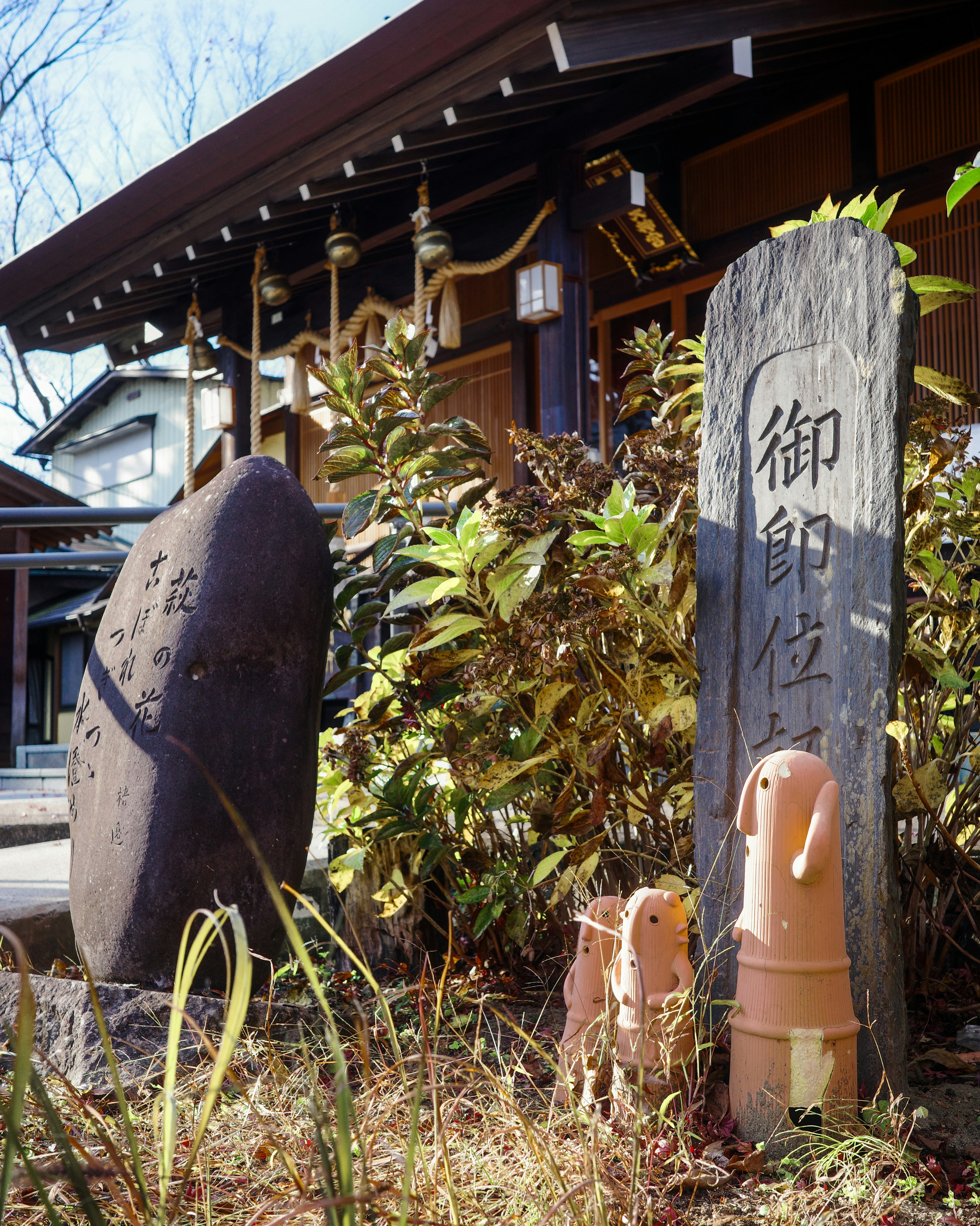 御札のような石板と花のある庭先