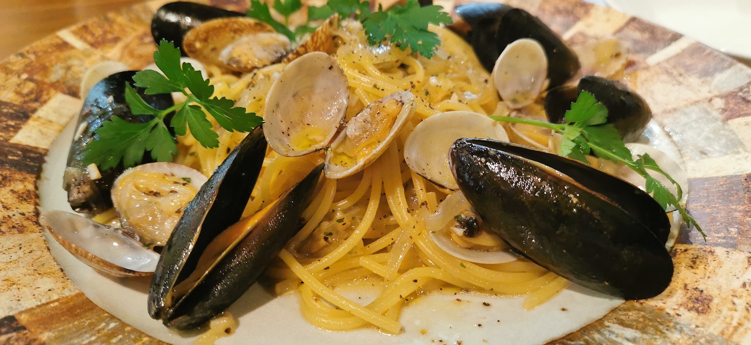 Plato de pasta con mejillones y almejas decorado con perejil